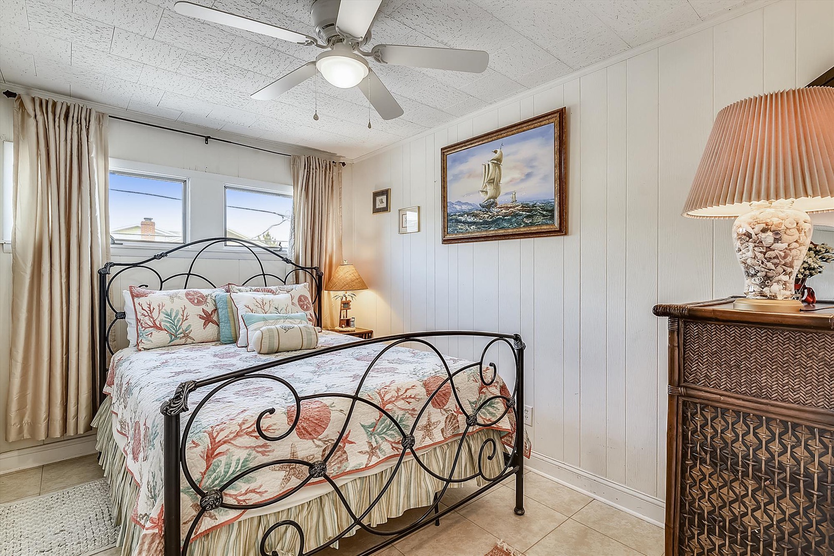 Wake to gentle coastal breezes under your ceiling fan in this charming bedroom adorned with nautical touches. Sink into plush bedding while ocean-inspired artwork reminds you the beach awaits just outside.