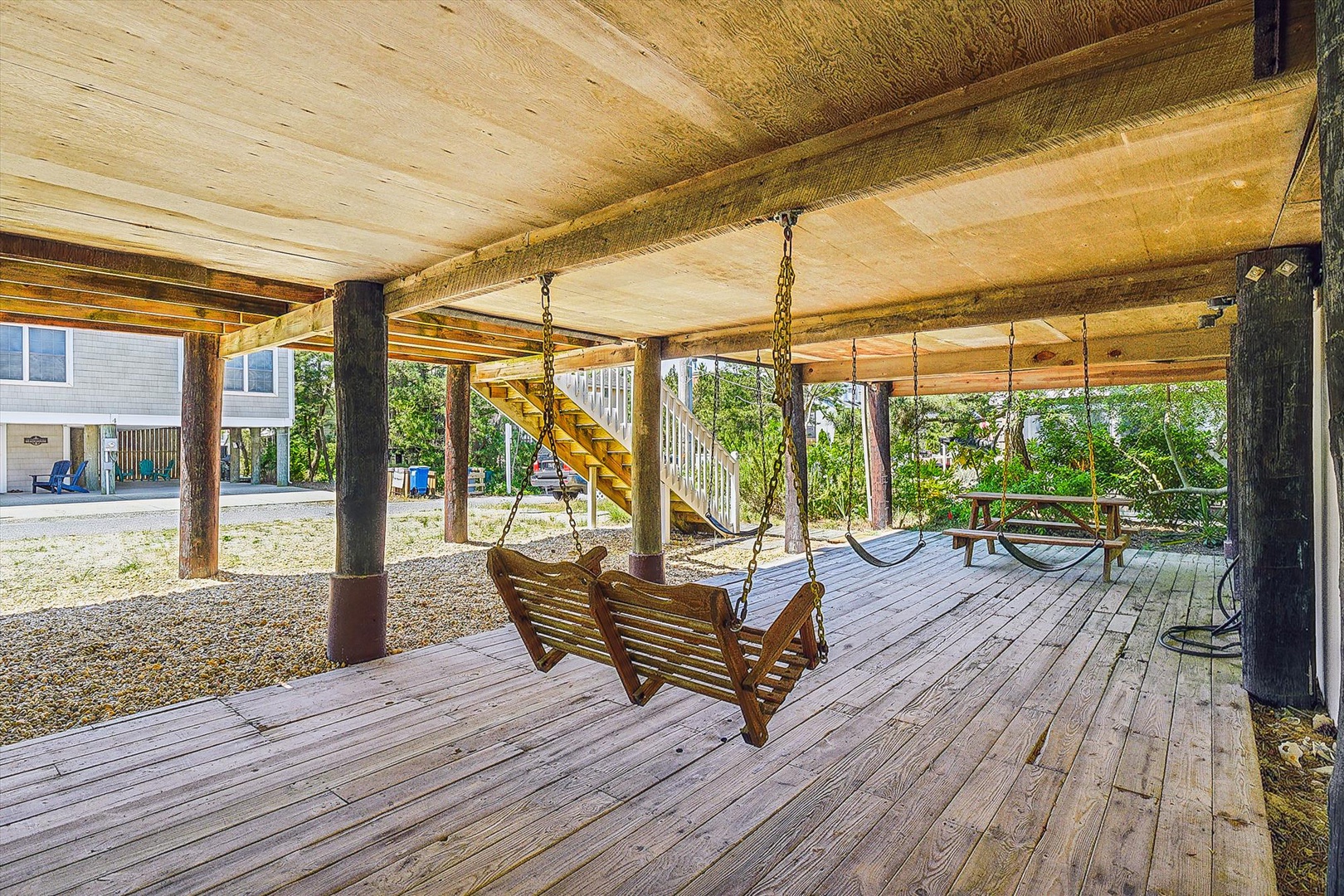 Picture yourself swaying gently on wooden bench swings beneath the shaded deck, surrounded by lush greenery and the soothing sounds of nature—your perfect spot to unwind and reconnect.
