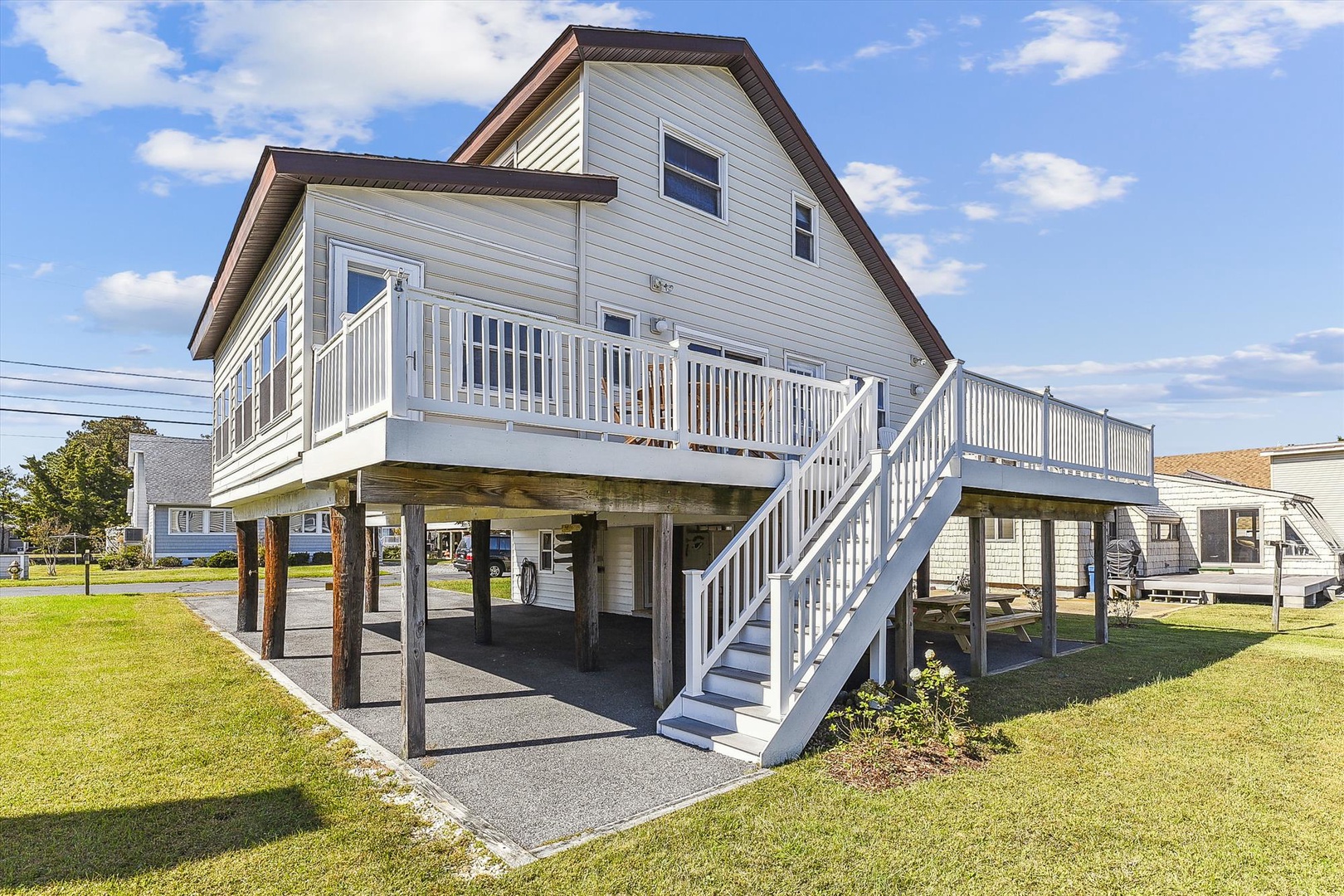 A coastal vacation home elevated on sturdy pilings with a welcoming balcony and covered parking below, set in a peaceful residential neighborhood near the shore.