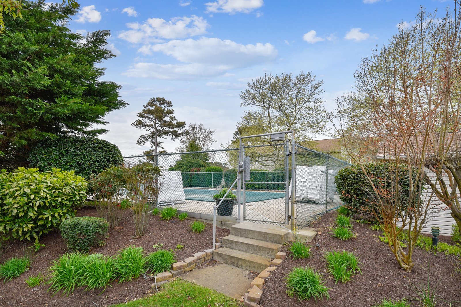 The property features a private tennis court surrounded by well-maintained gardens and mature trees, offering guests an active outdoor amenity in a peaceful, natural setting.