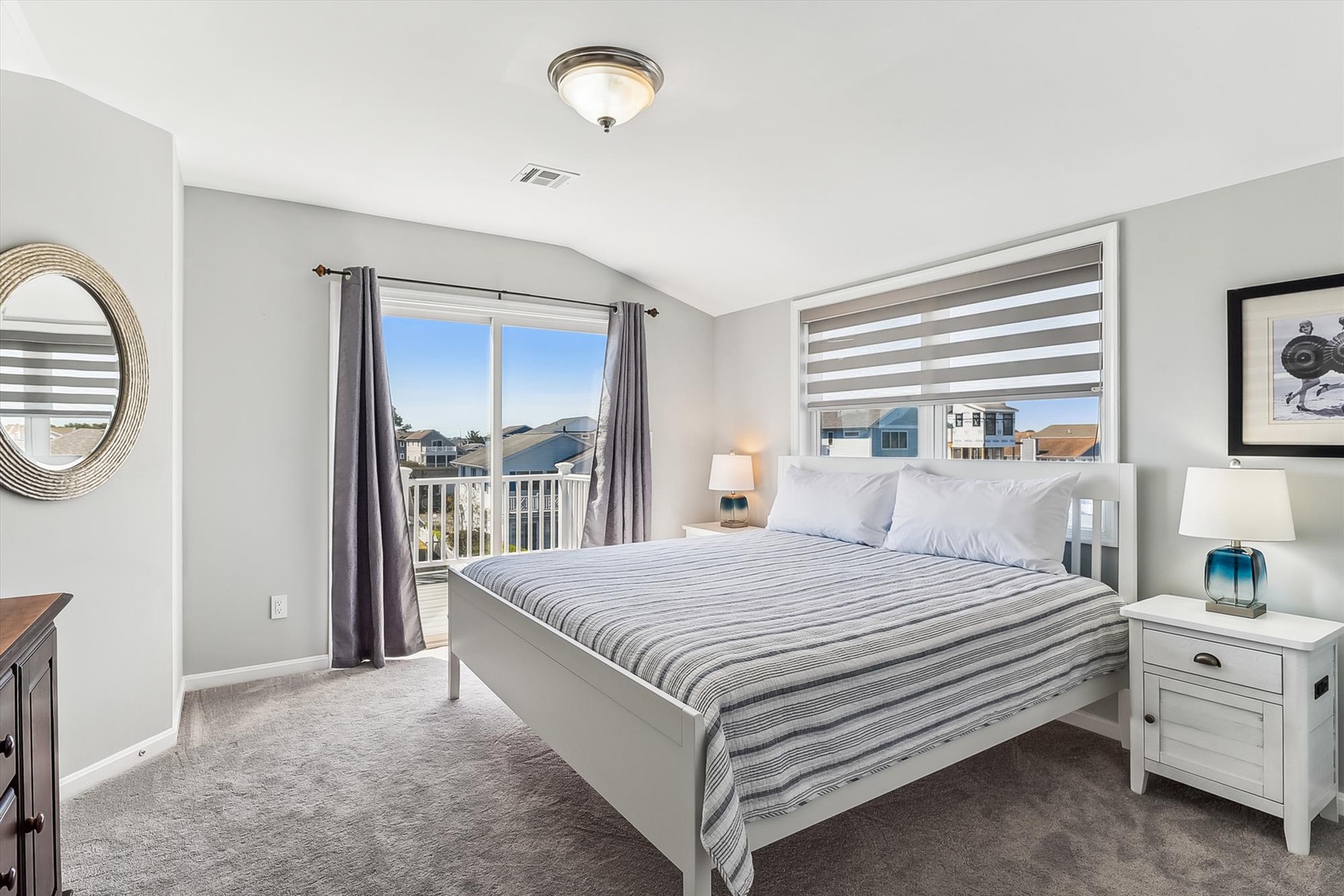 Unwind in your serene bedroom where soft light pours through large windows, illuminating crisp linens and coastal-inspired decor that invite restful sleep.