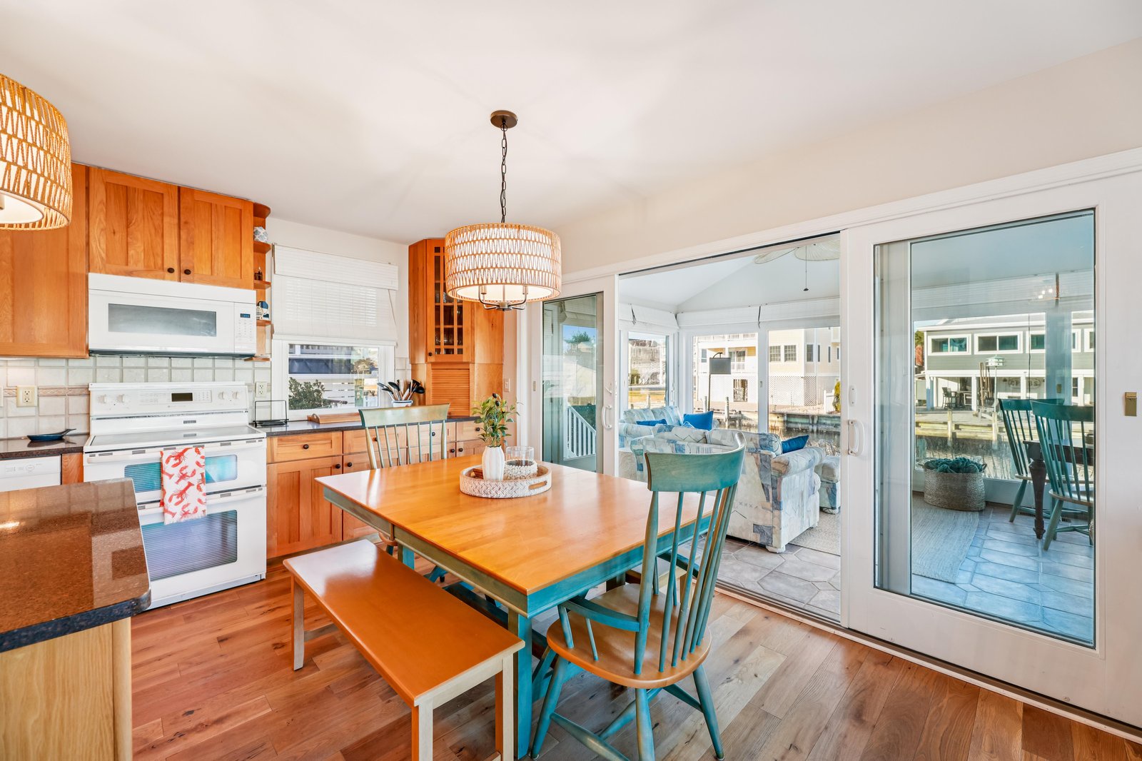 Gather around the warm wood dining table in this bright, coastal-style kitchen and enjoy easy access to the sunlit patio just beyond the glass doors.