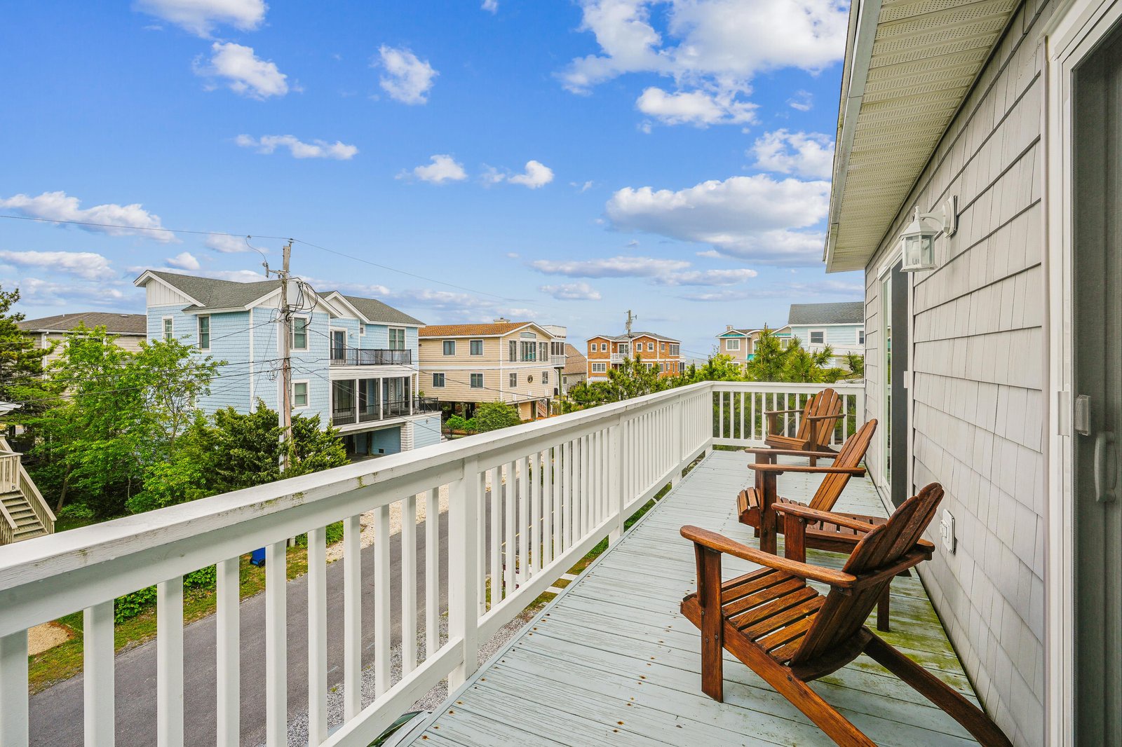 Picture yourself sinking into these wooden Adirondack chairs, feeling the coastal breeze as you watch the neighborhood come to life. This spacious deck offers your own private perch to enjoy morning coffee or evening conversations under open skies.