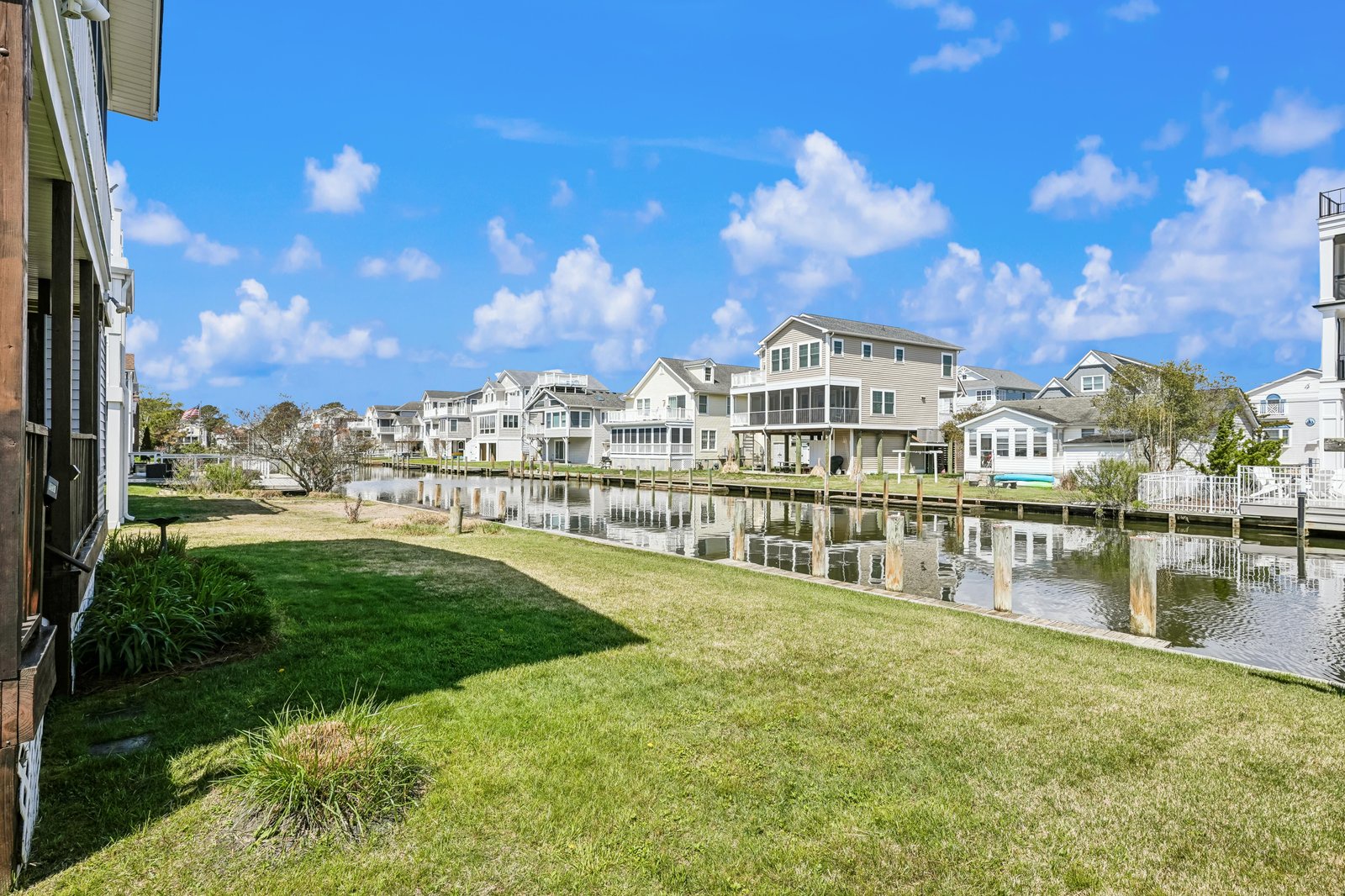 Waterfront neighborhood with canal access and private docks, surrounded by coastal homes and lush green lawn under a bright blue sky.