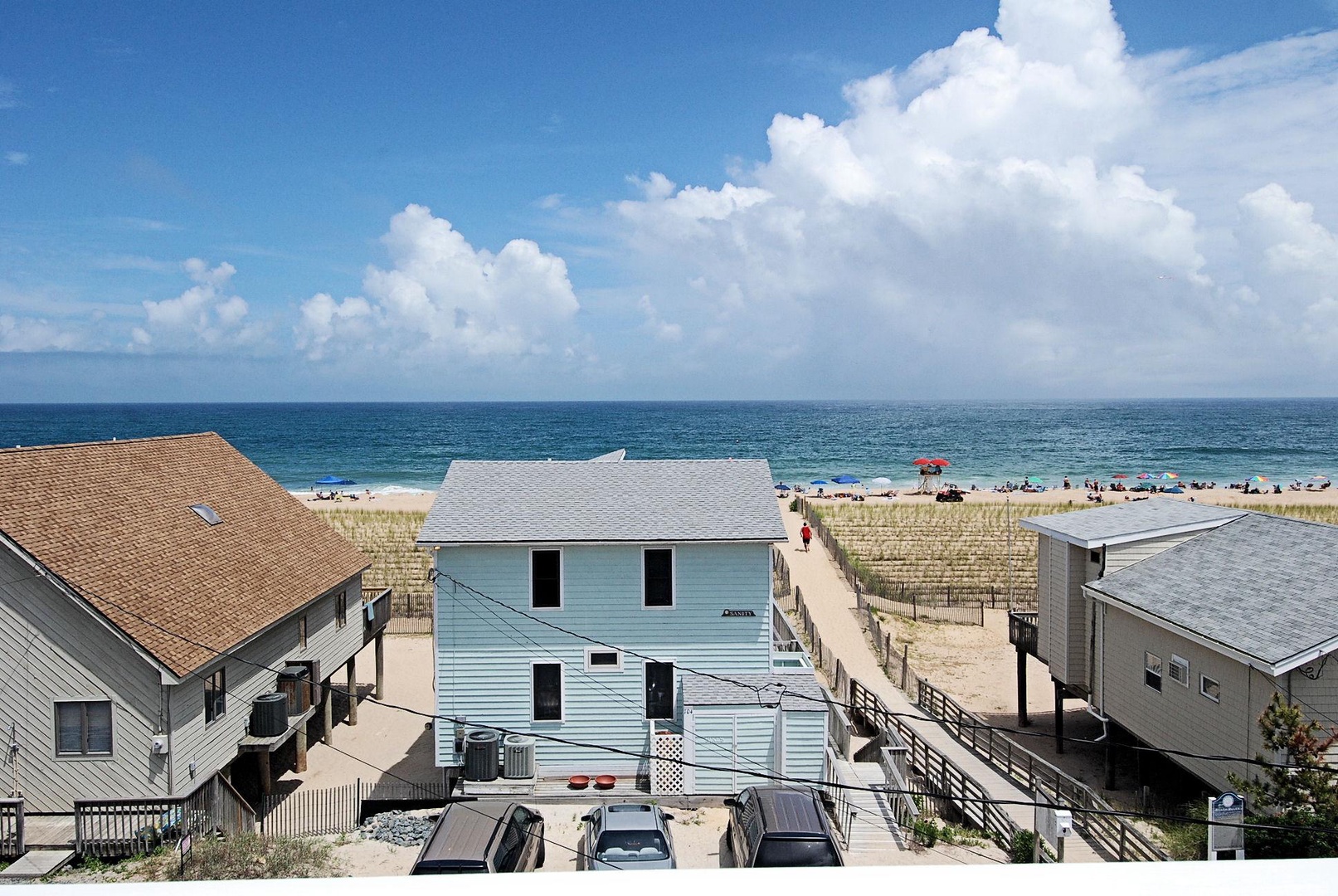 Beachfront vacation homes nestled along the coast, offering direct sandy beach access and stunning ocean vistas under a brilliant blue sky.