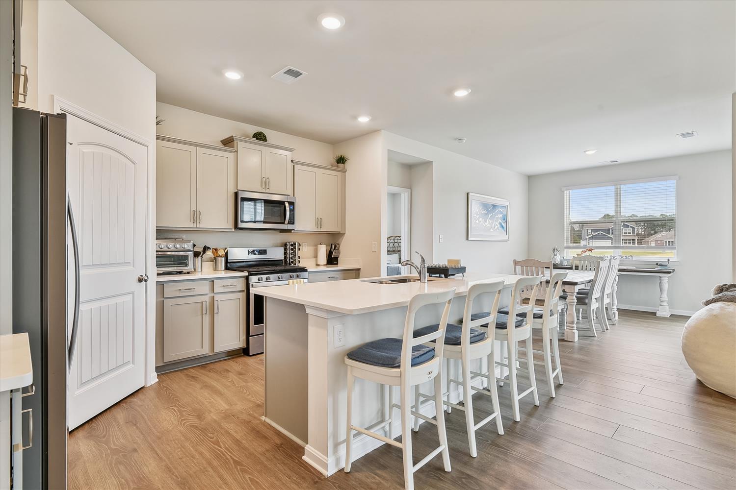 Gather with loved ones in this bright, open-concept kitchen and dining area, where a spacious island invites laughter and shared meals as sunshine streams through expansive windows.