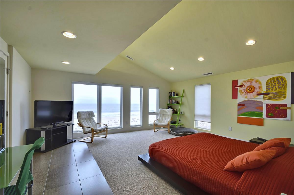Bright vaulted ceilings frame your spacious bedroom retreat, where picture windows invite the ocean into your morning routine and cozy seating beckons you to unwind by the view.