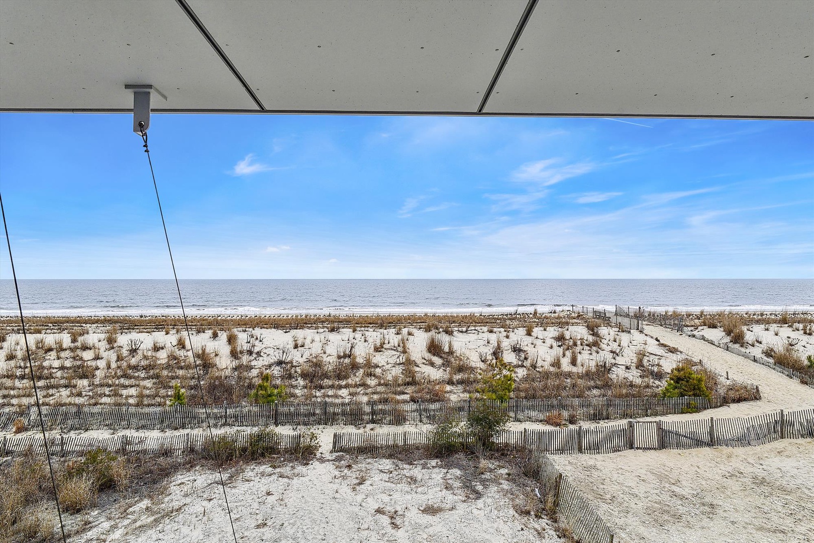 Beachfront property with direct access to white sand dunes and ocean views. A wooden walkway leads through protected coastal vegetation to the shoreline.