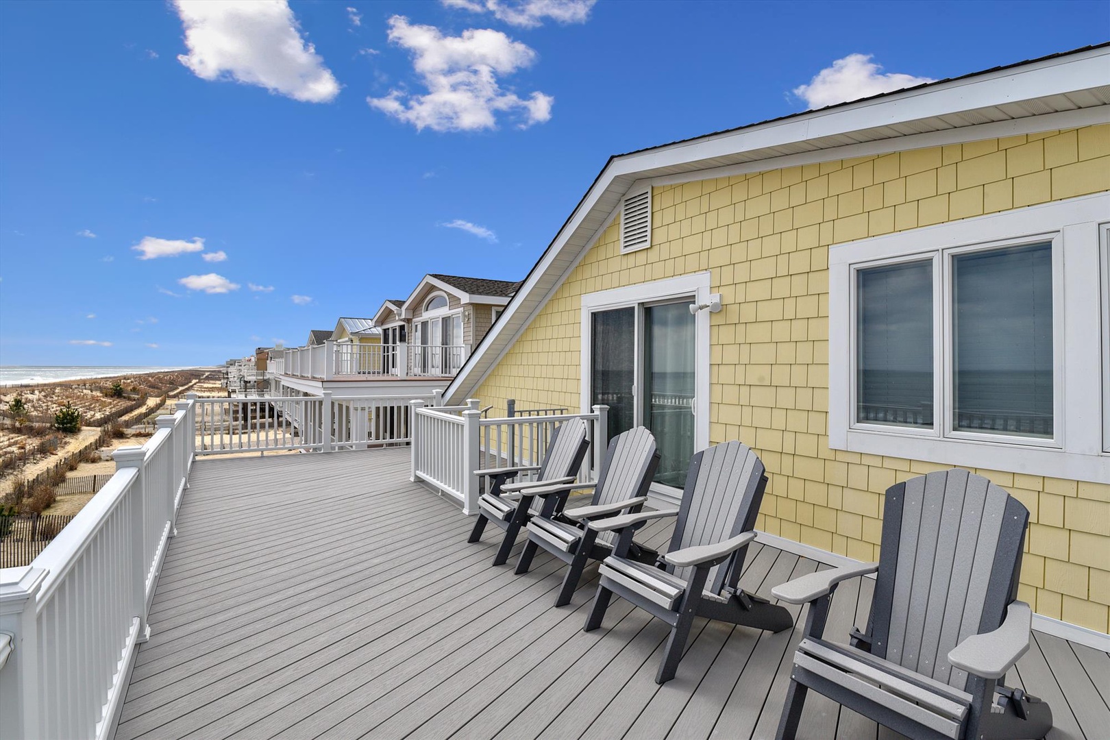 Spacious oceanfront deck with comfortable Adirondack chairs where you can unwind and soak in coastal breezes and stunning beach views.