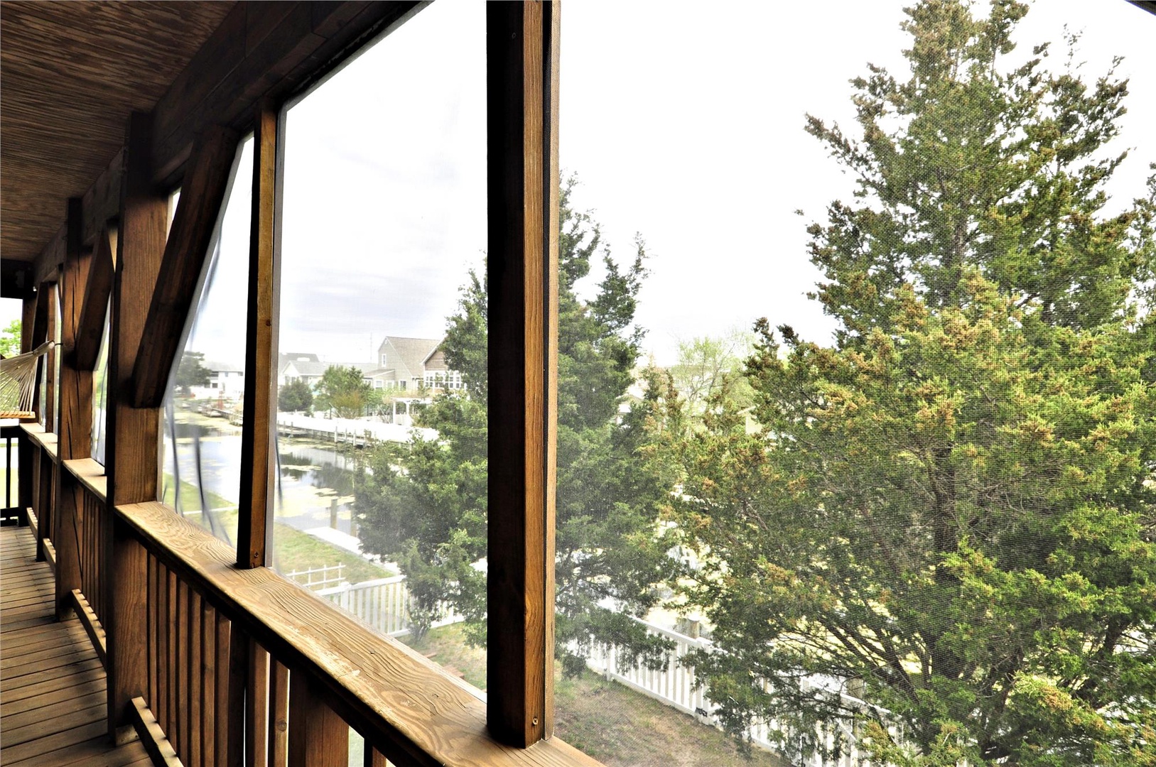 Screened balcony framing peaceful waterfront and neighborhood views, ideal for morning coffee or evening relaxation.