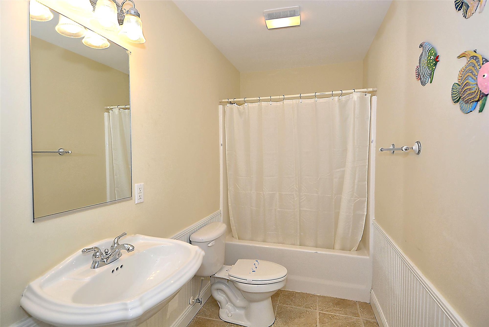 Step into your private bathroom featuring a full tub-shower combo, bright lighting, and cheerful tropical fish décor to brighten your mornings.