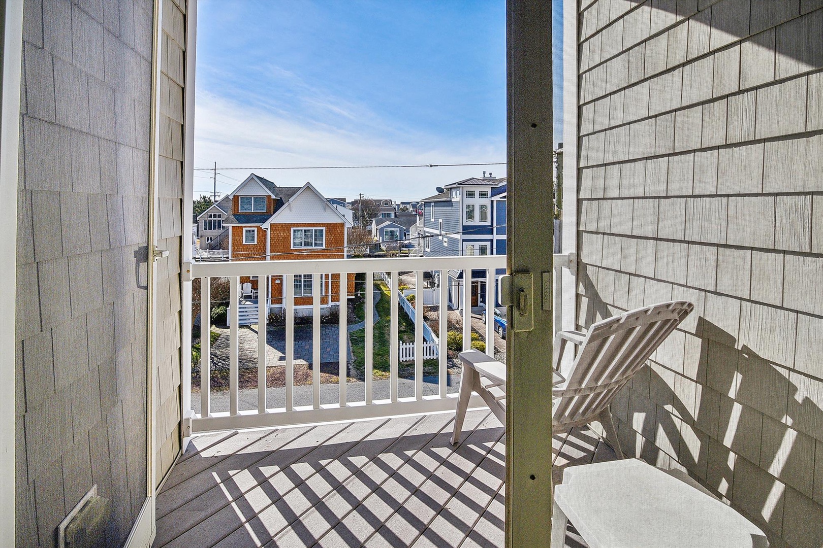 Charming coastal neighborhood surrounds this property, with colorful beach houses and a peaceful residential setting visible from the balcony area.