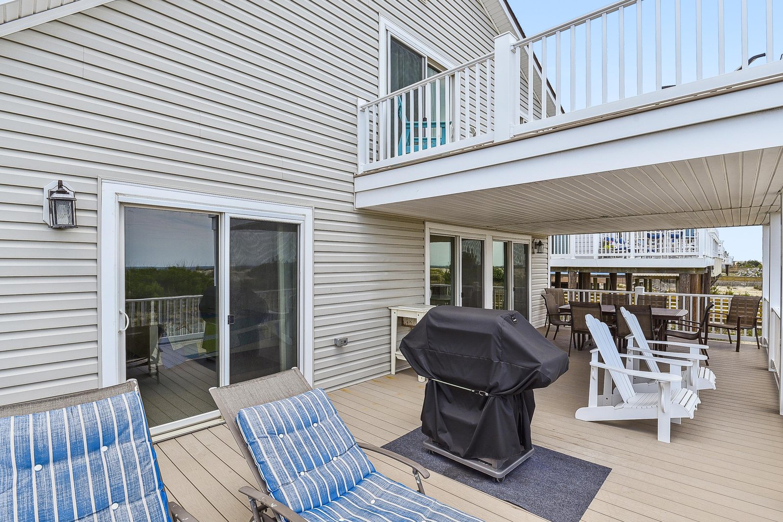 Your private deck stretches out under a covered overhang with lounge chairs, a grill ready for cookouts, and Adirondack chairs overlooking the surrounding area—perfect for relaxing mornings and breezy evenings outdoors.