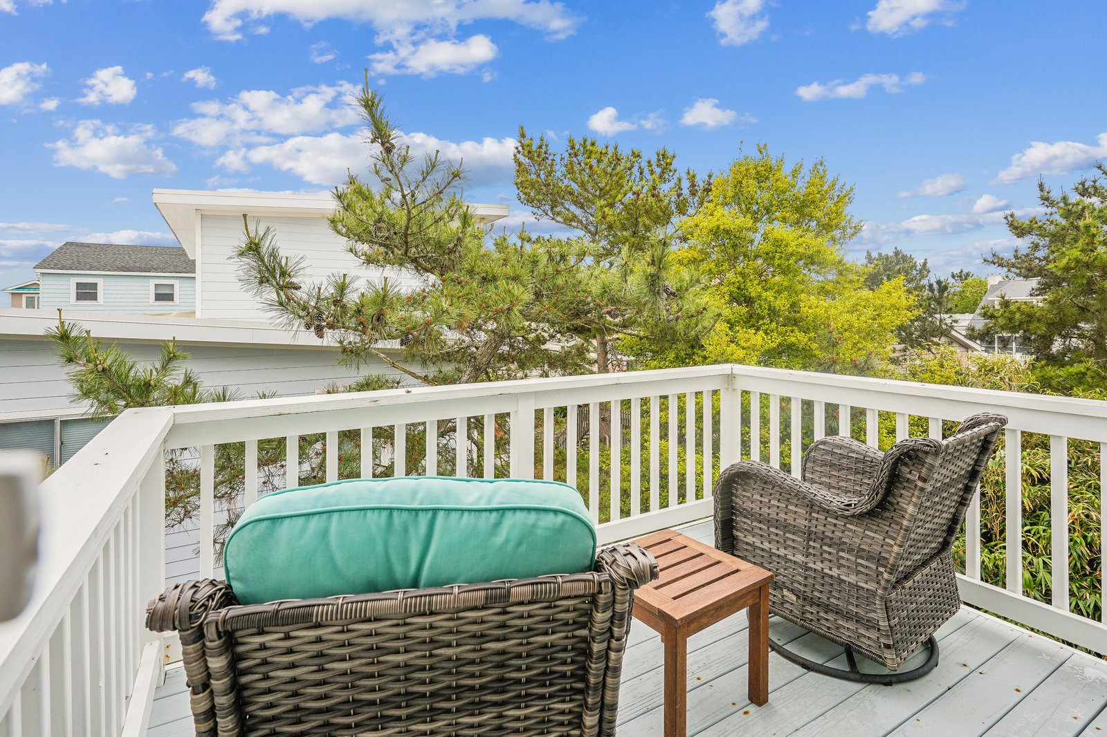 Picture yourself unwinding on your private balcony, surrounded by lush greenery and soft coastal breezes. Comfortable seating invites relaxation as you soak in peaceful treetop views under open skies.