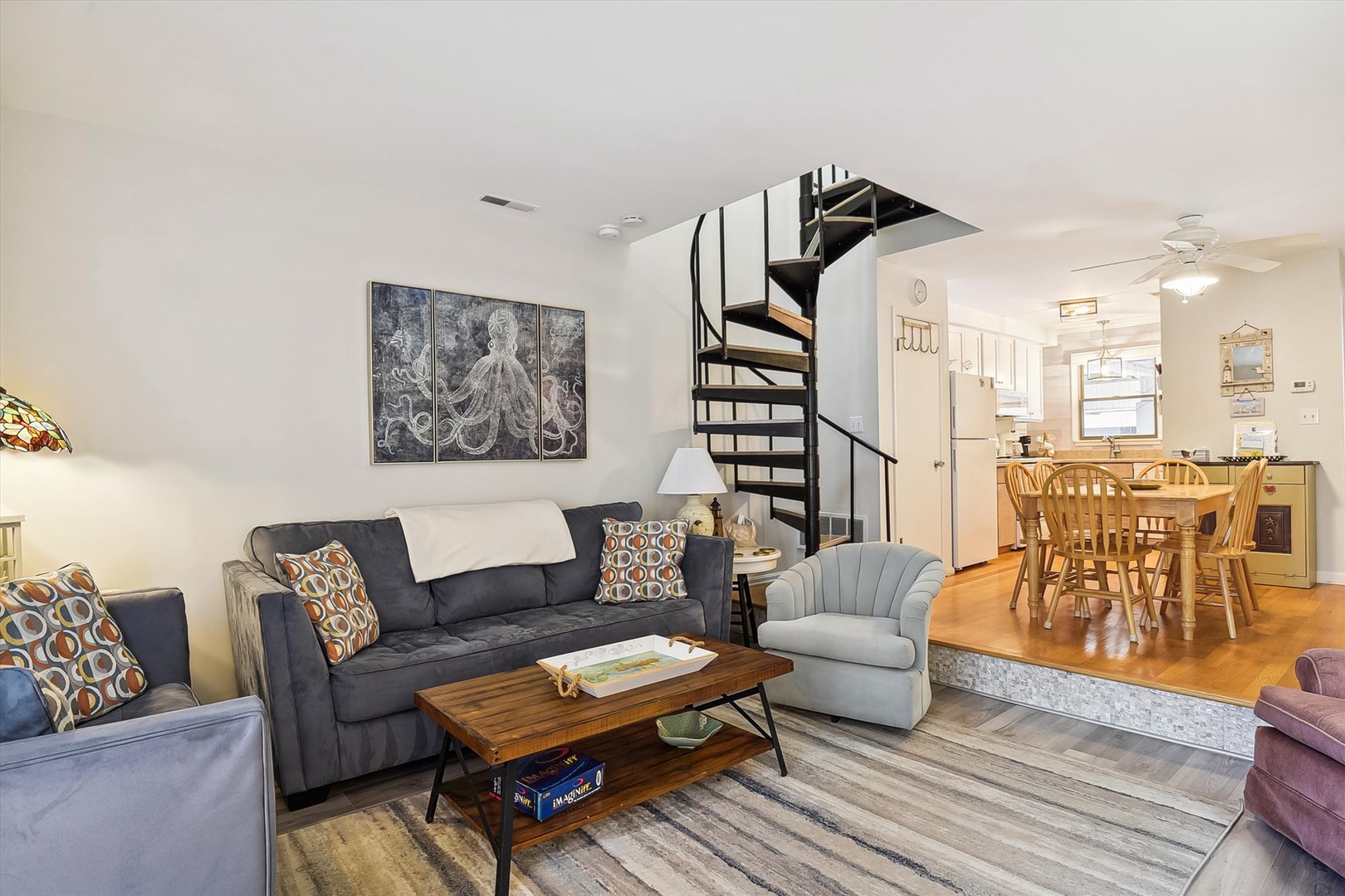 Relax in your spacious living room with coastal-inspired décor, a spiral staircase to added space, and an inviting dining area perfect for meals together.