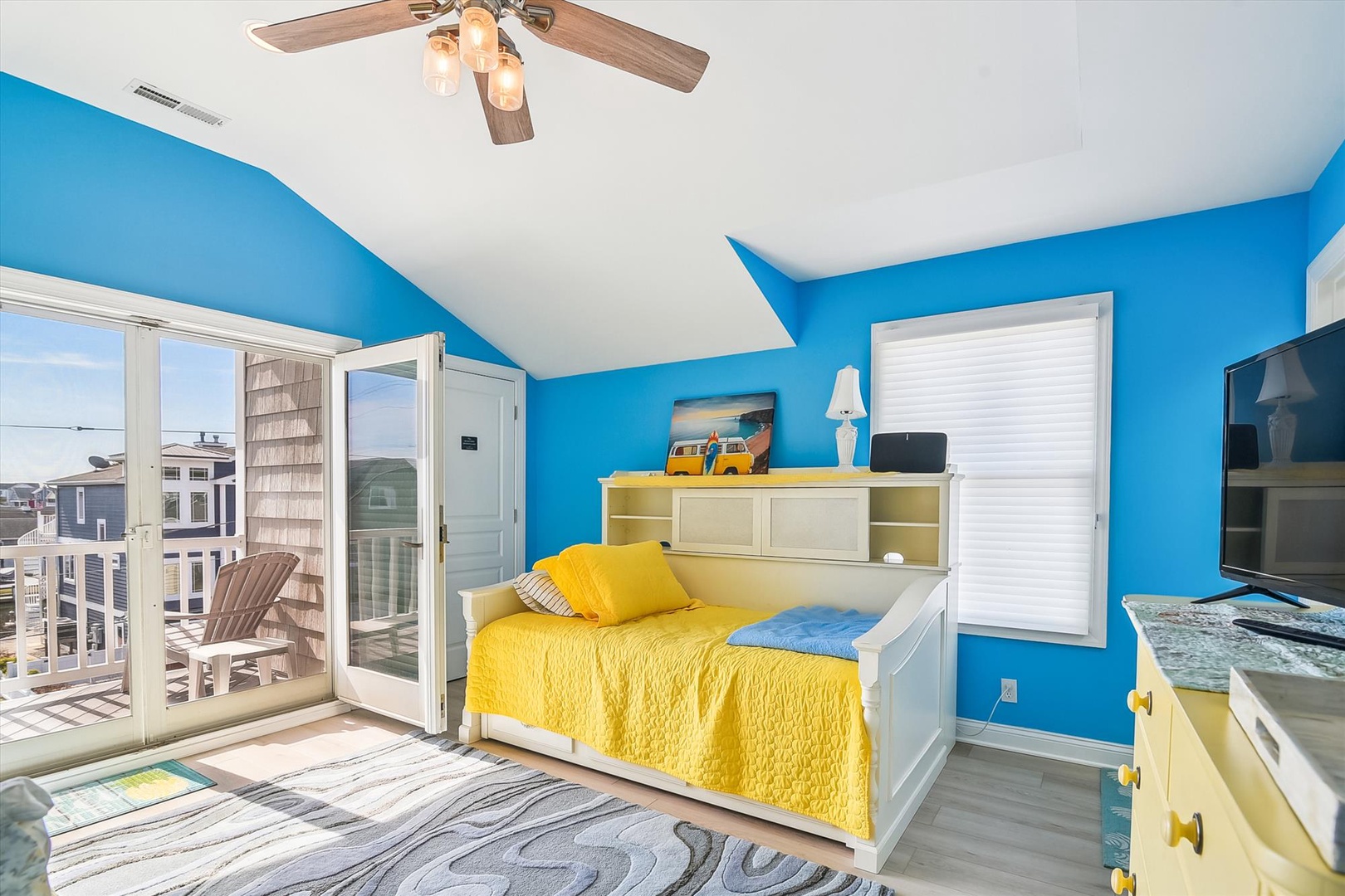Vibrant beach-themed bedroom with sunny yellow bedding, ocean-blue walls, and your own private balcony offering refreshing coastal breezes.