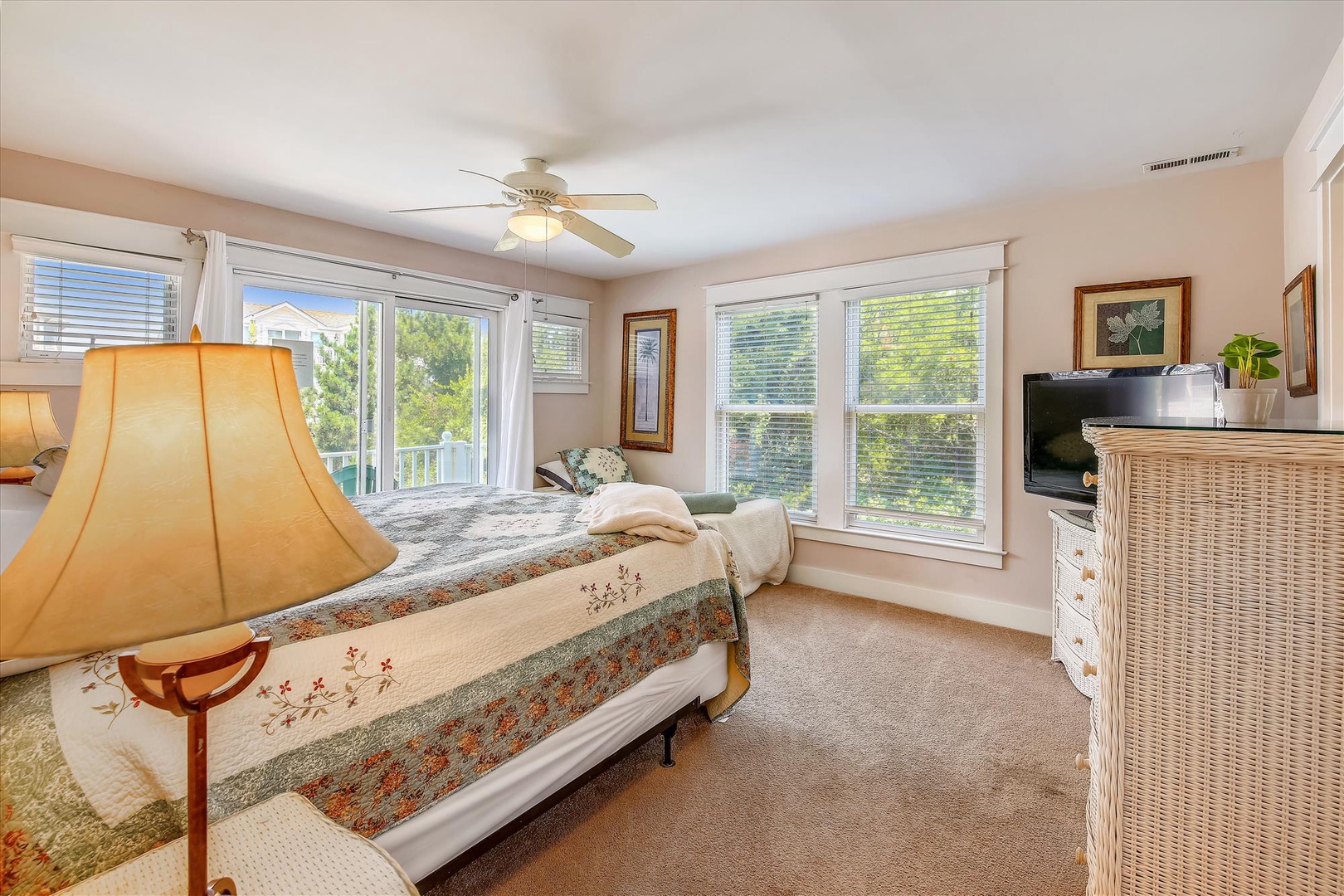 Sink into the plush bed and wake to natural light streaming through large windows overlooking lush greenery. Relax under the ceiling fan with your favorite shows on the flat-screen TV.