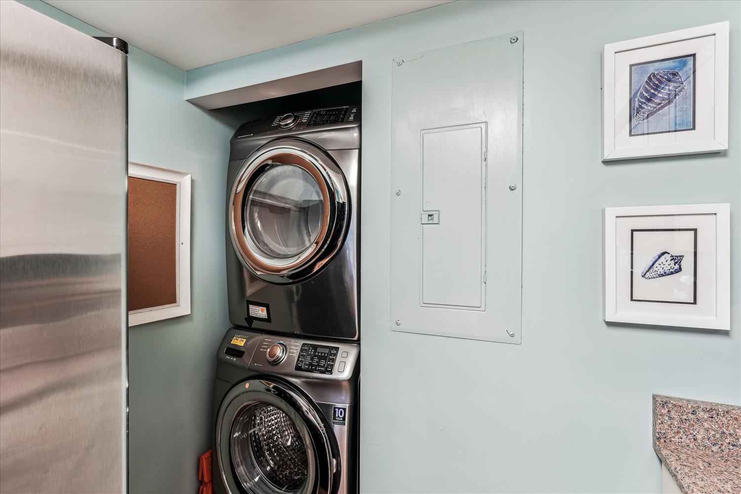 Your in-unit washer and dryer make extended stays effortless, tucked neatly into a coastal-inspired alcove with serene aqua walls and charming shell artwork.