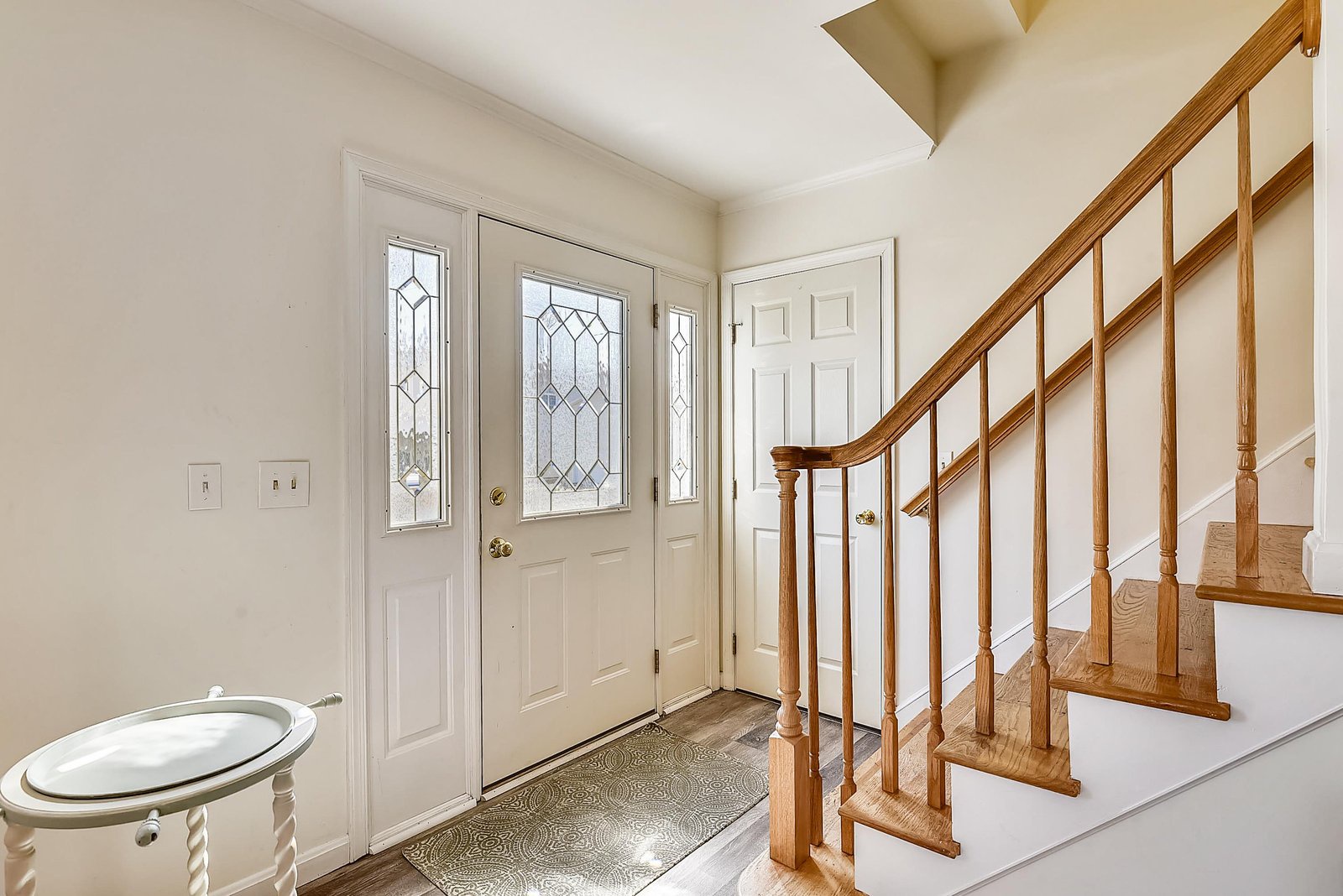 Step into your welcoming entryway with elegant leaded glass windows that flood the space with natural light. The warm oak staircase and soaring ceiling create an open, airy feel from the moment you arrive.