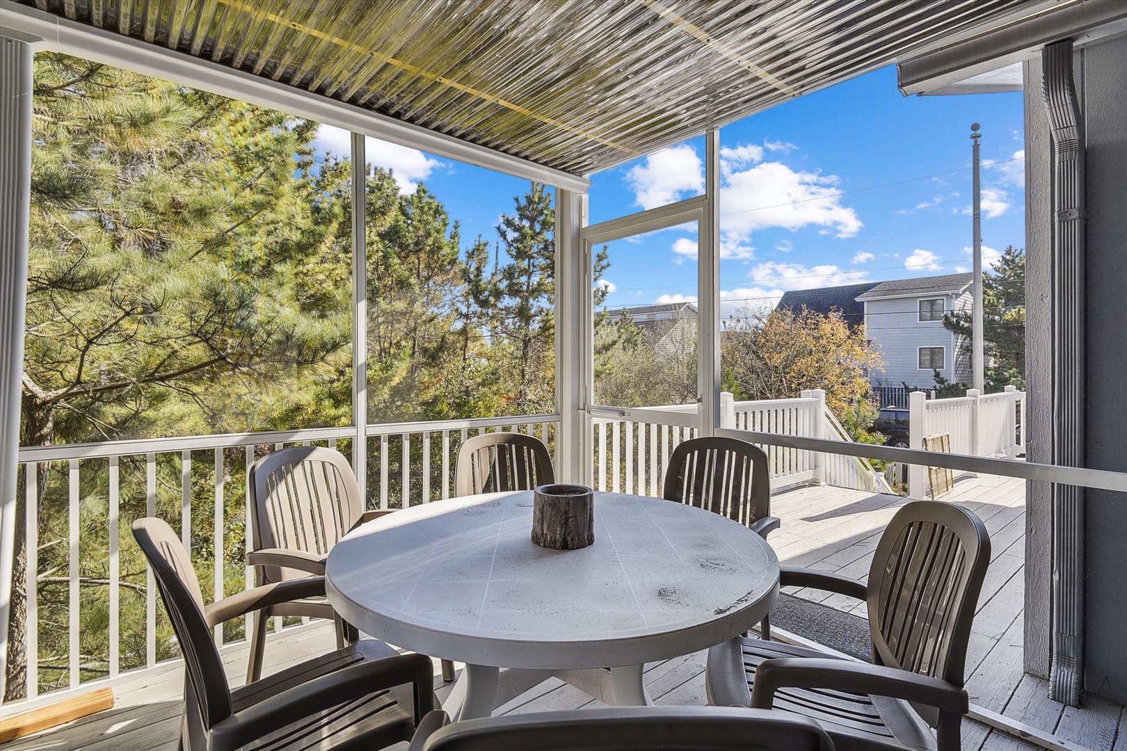Enjoy morning coffee or evening meals on your screened balcony, where a round dining table for four awaits. Through large windows, natural light floods in alongside peaceful views of greenery and neighboring homes.