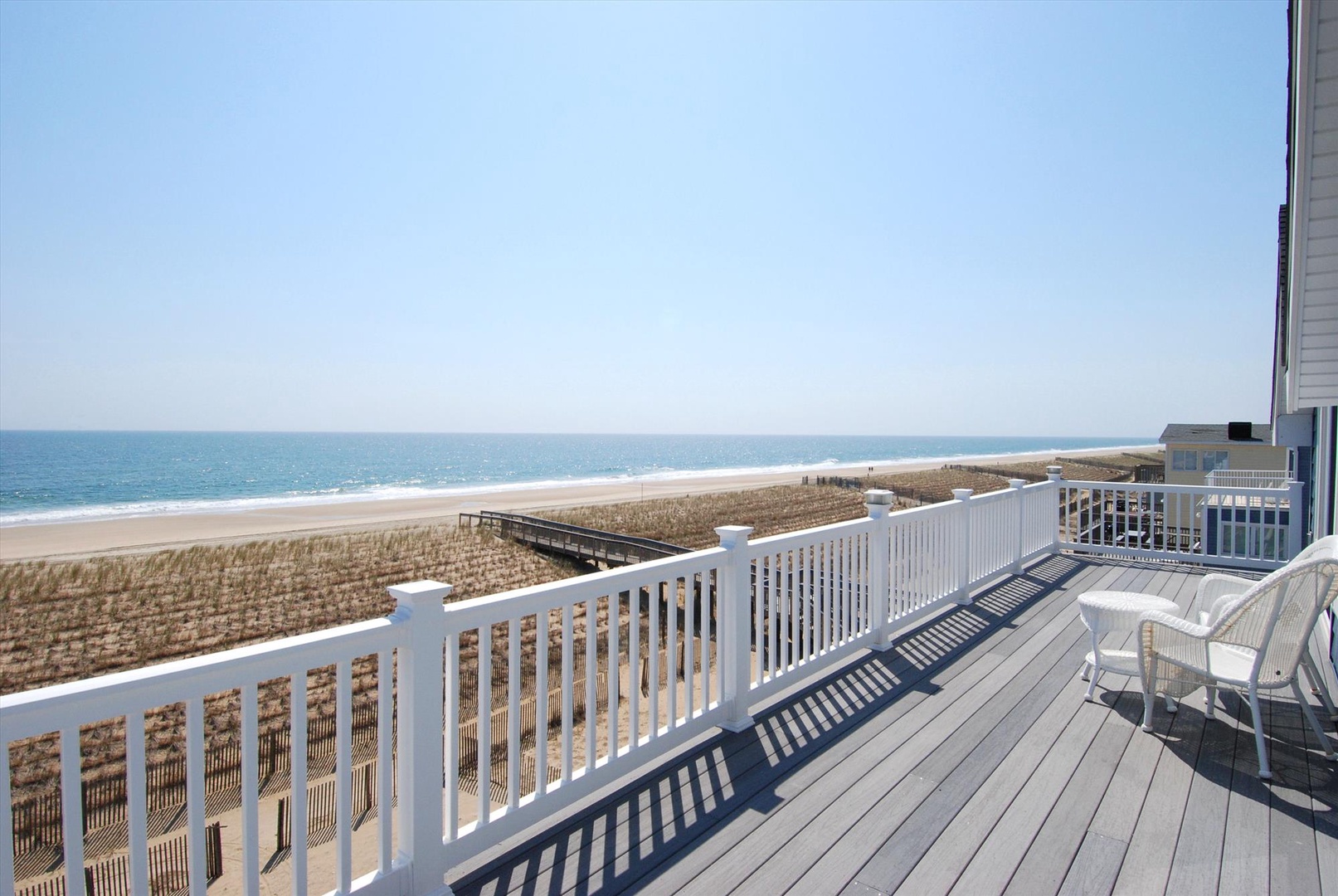 Beachfront deck offering direct sandy shore access with ocean views, dune boardwalk, and comfortable outdoor seating for coastal relaxation.