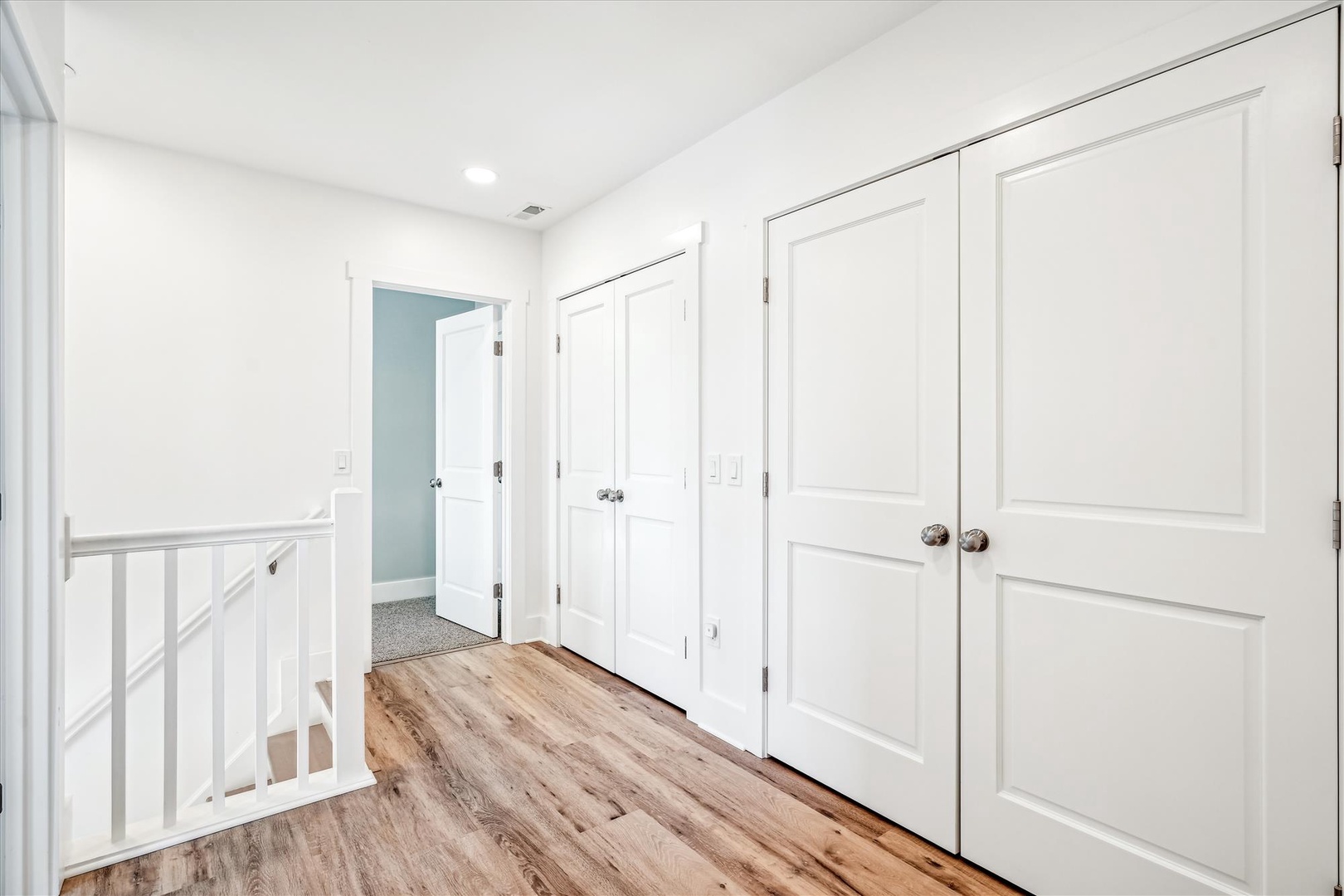 Clean white hallway with warm wood floors leads you to your private spaces, featuring built-in storage for all your belongings.