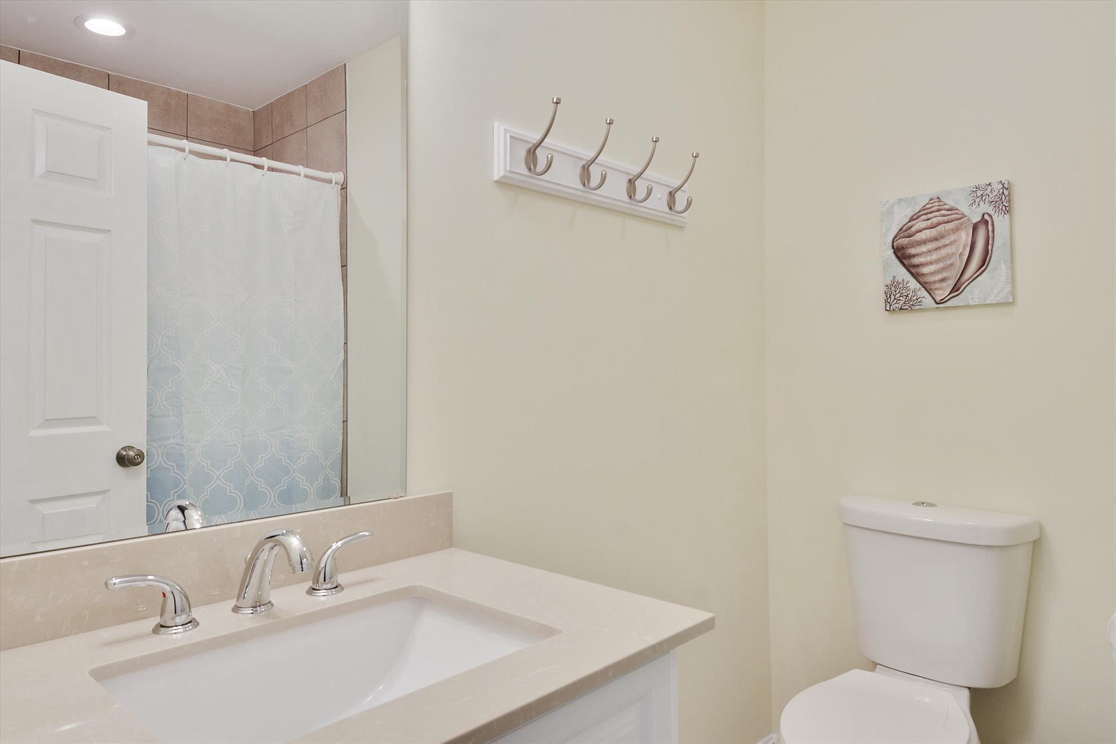 Freshen up in your private bathroom, featuring a clean vanity, coastal accents, and convenient hooks for your towels and personal items.