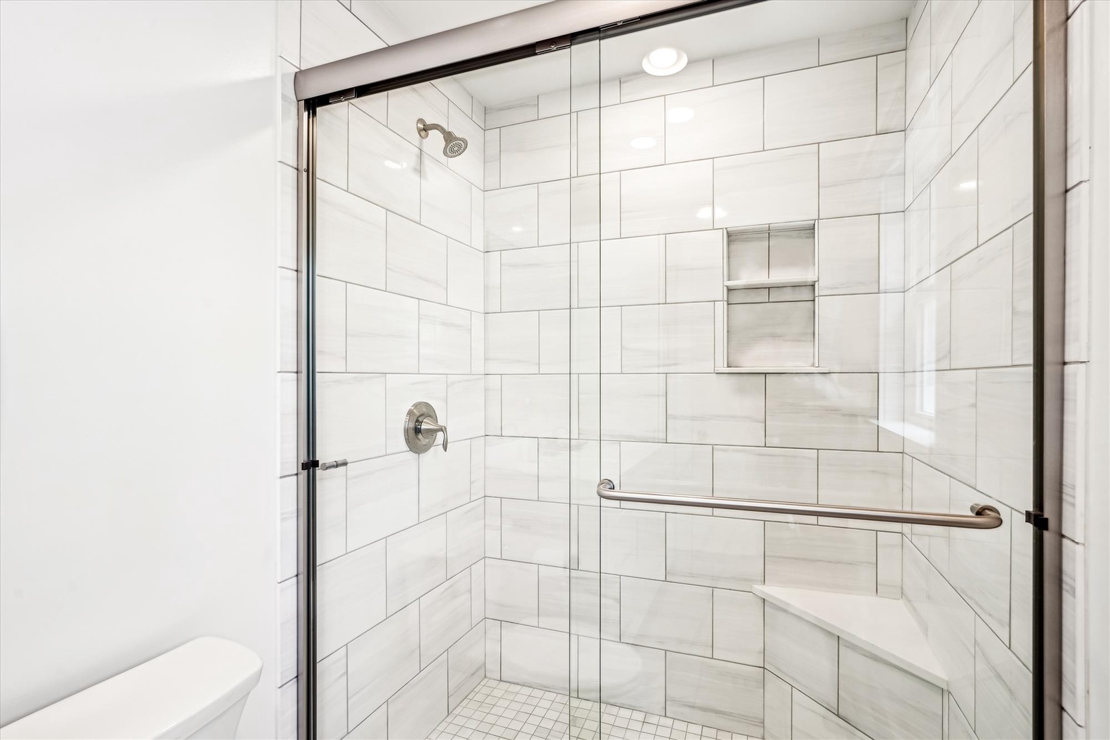 Step into your pristine walk-in shower with elegant white subway tiles and modern glass doors for a refreshing start to your day.