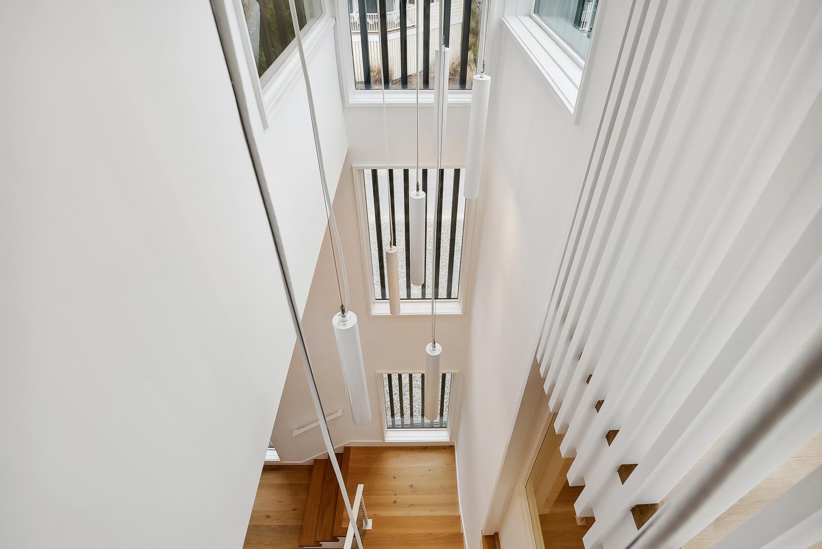 Bright, open stairwell flooded with natural light from above, creating a warm and airy entryway.