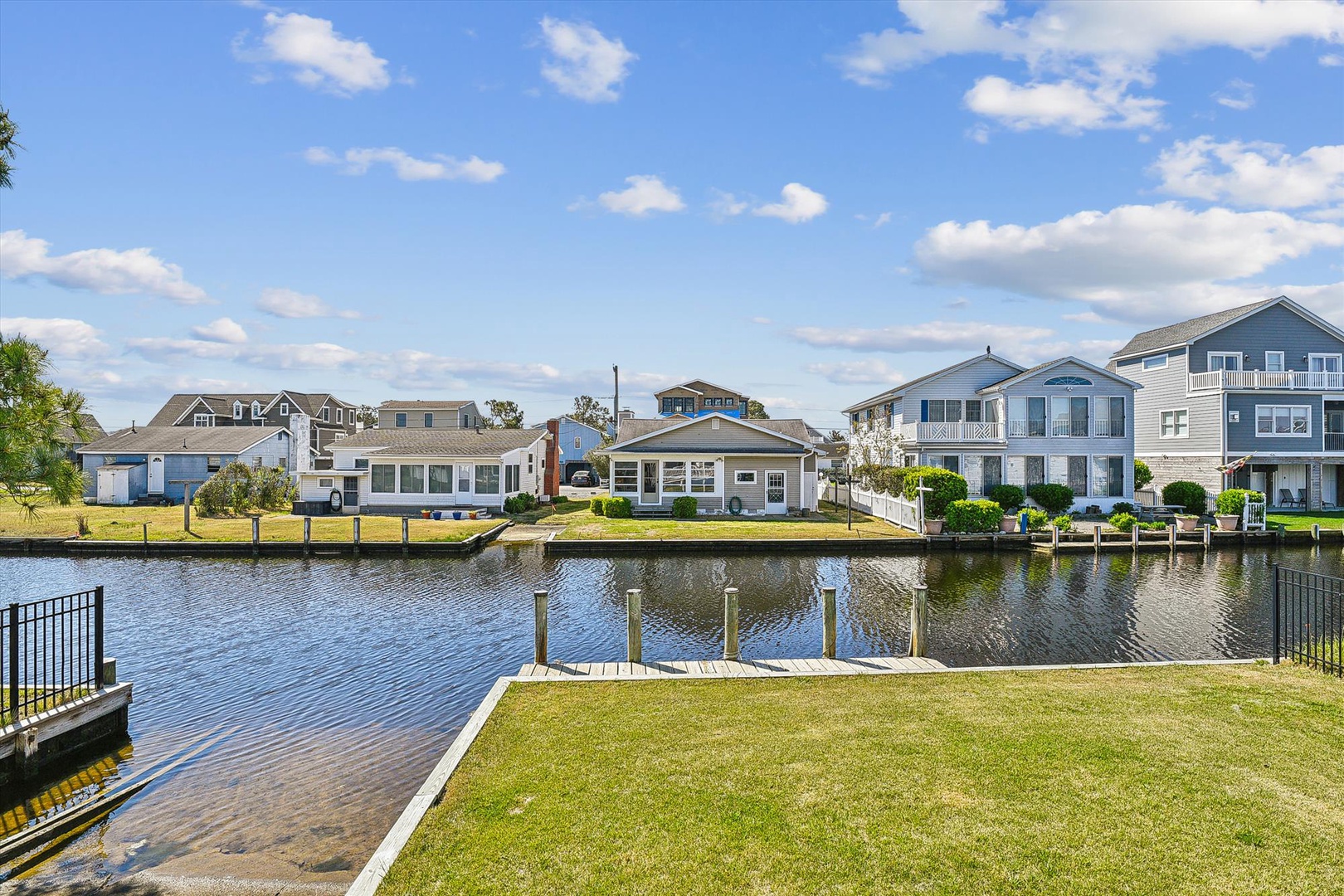 Waterfront property on a tranquil canal in a residential coastal neighborhood, featuring private dock access and scenic views of nearby homes under clear skies.