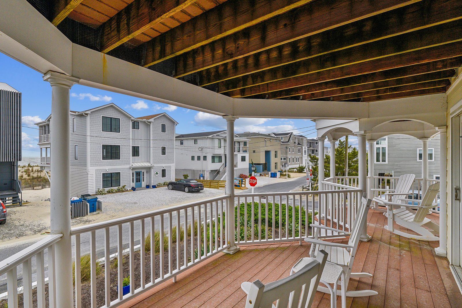 Relax in your private outdoor space under a striking wood-beamed ceiling, where comfortable seating invites you to unwind with views of the coastal neighborhood.