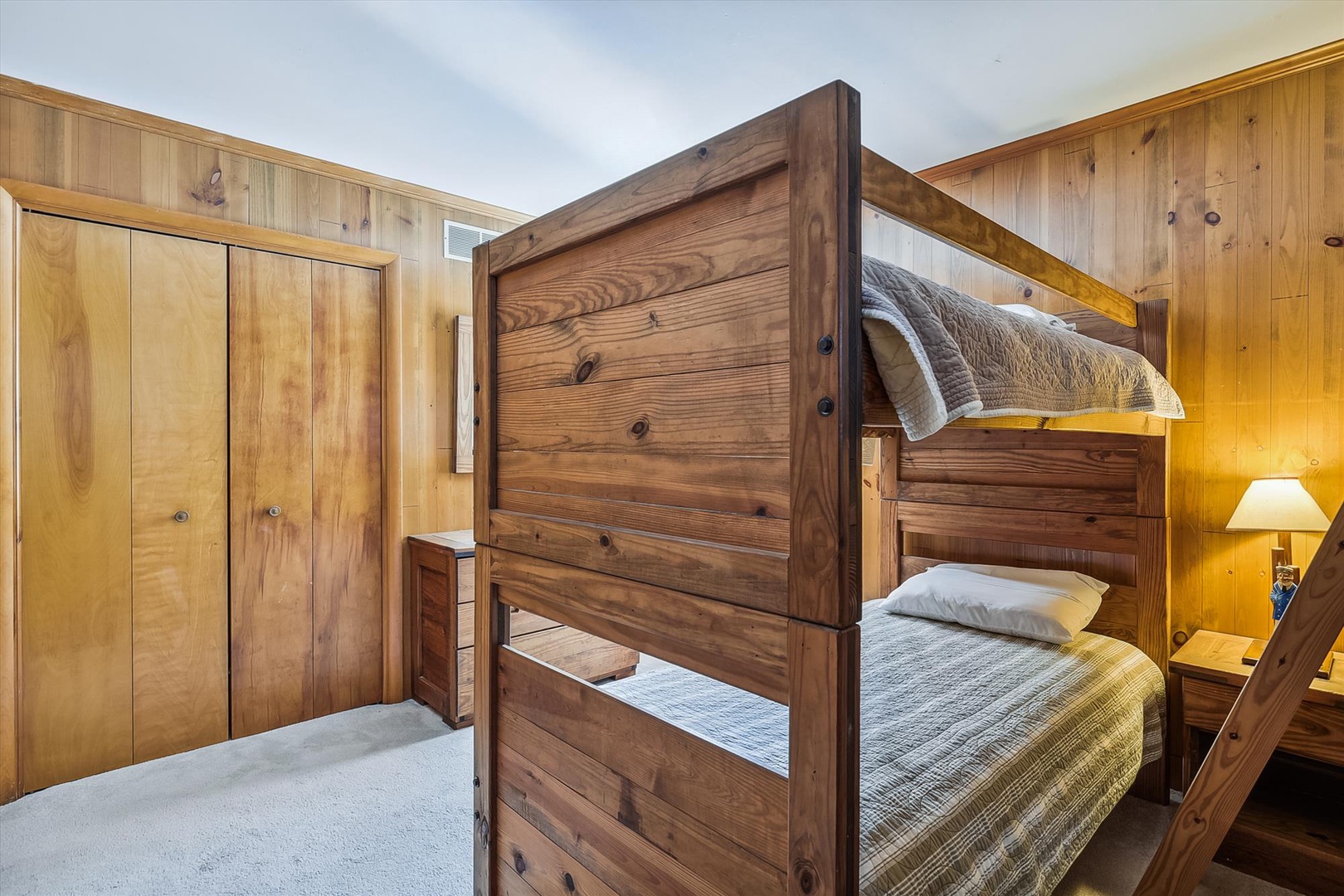 Your kids will love this cozy bunk room with warm wood paneling and soft bedding—perfect for creating vacation memories together.