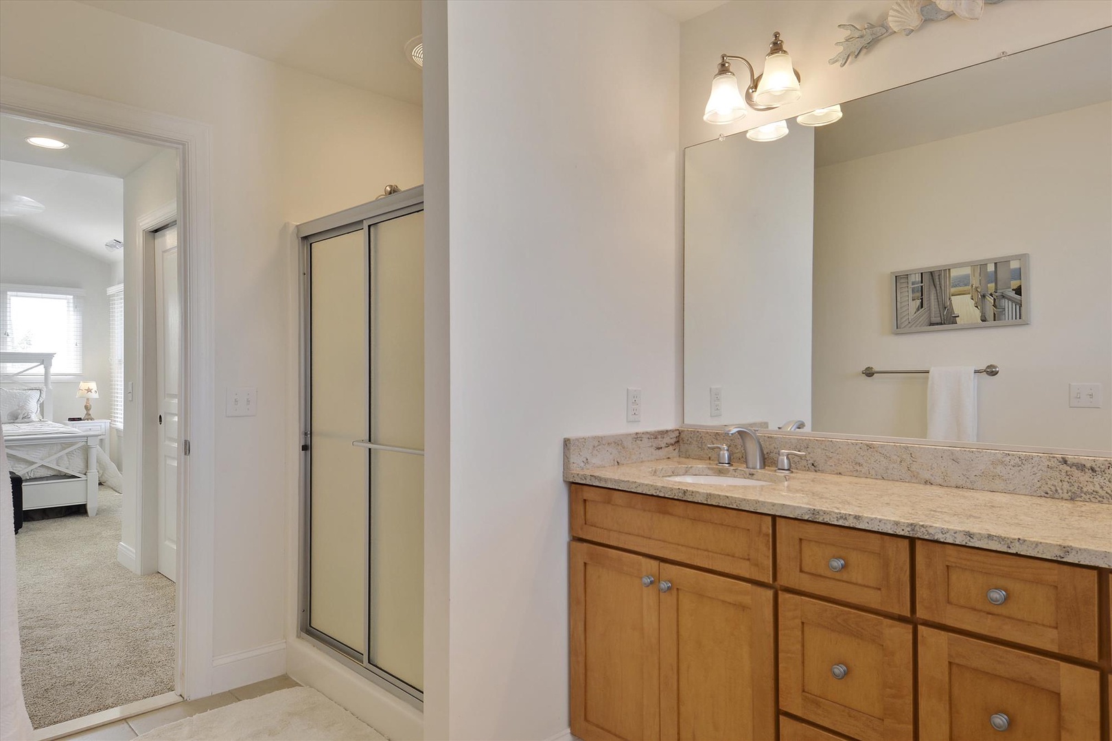 Your spacious bathroom features granite countertops, warm wood cabinetry, and a glass-enclosed shower for comfortable morning routines.