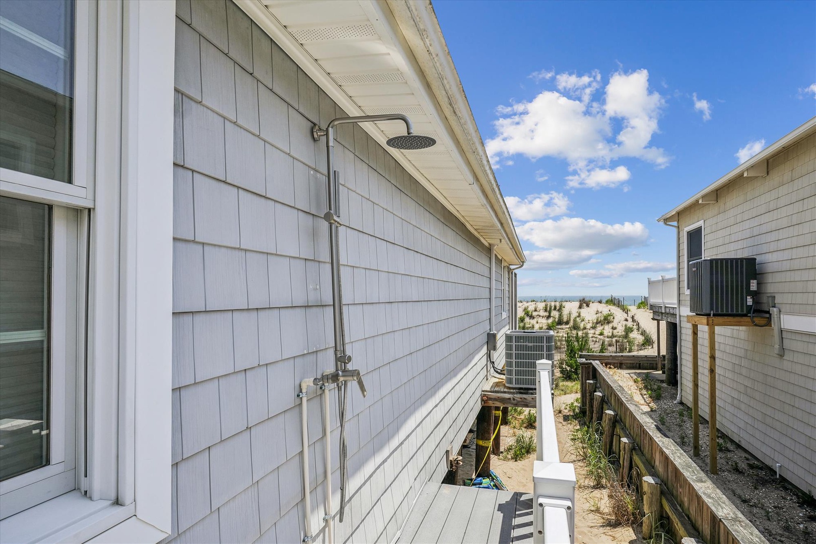 This property features an outdoor shower on the deck, offering a convenient rinse-off spot after a day of beach adventures under the wide-open sky.
