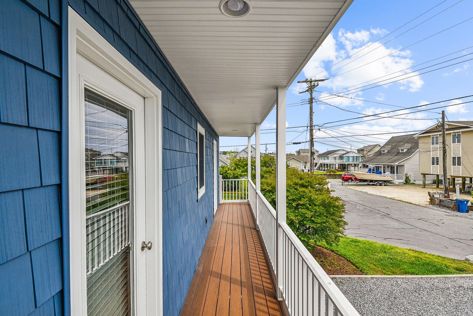 A welcoming covered balcony offering a quiet street view and glimpses of the surrounding coastal neighborhood.