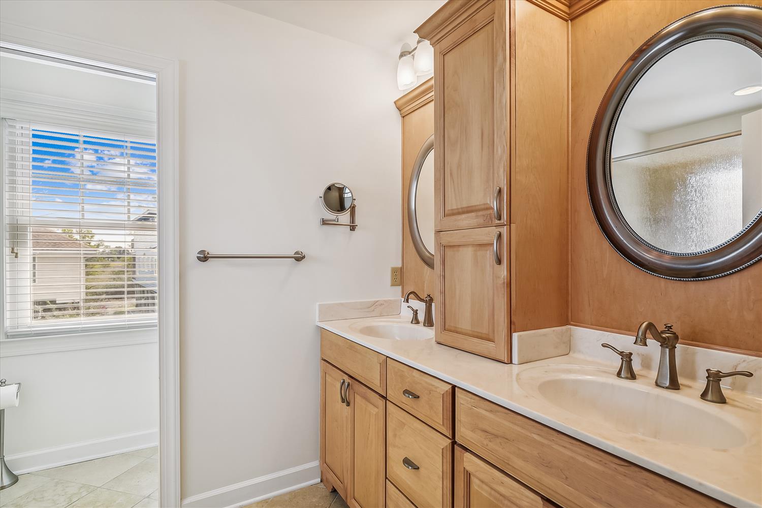 Freshen up at your dual-sink vanity with custom cabinetry and modern fixtures. The warm wood tones and thoughtful layout create a spa-like retreat where you can start and end each day feeling relaxed.