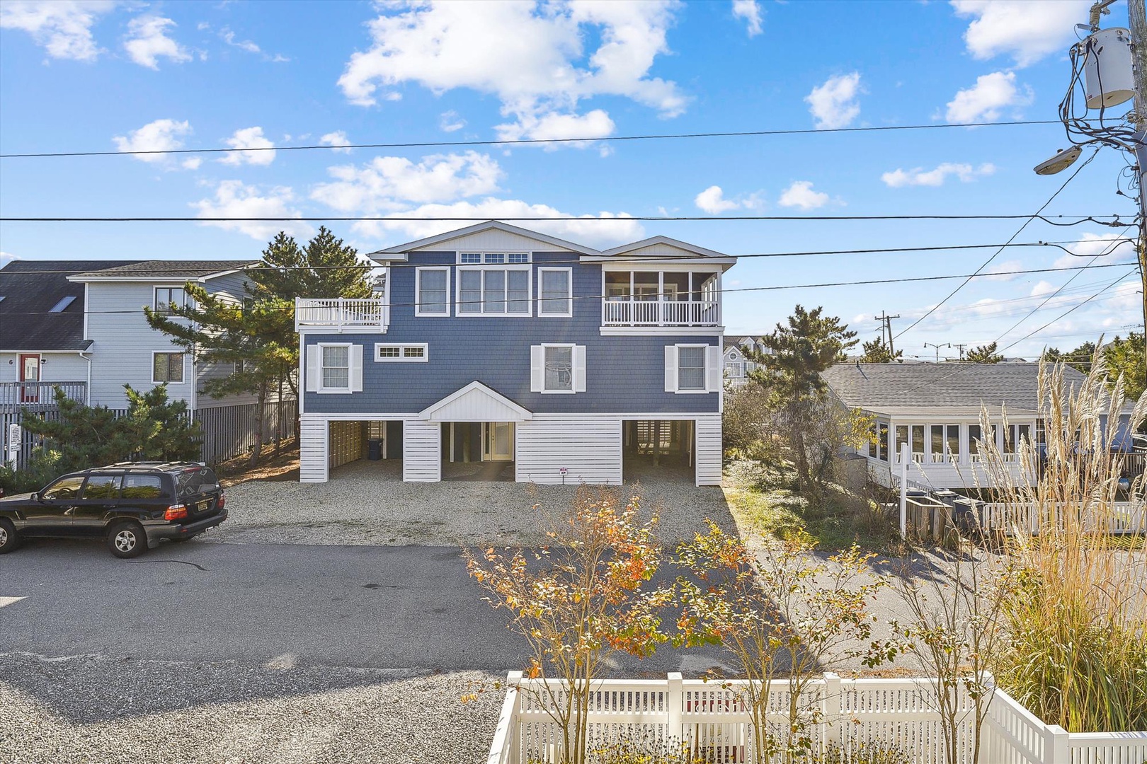 A charming coastal property featuring a three-story blue exterior with white trim, elevated design, and convenient parking in a peaceful residential neighborhood.