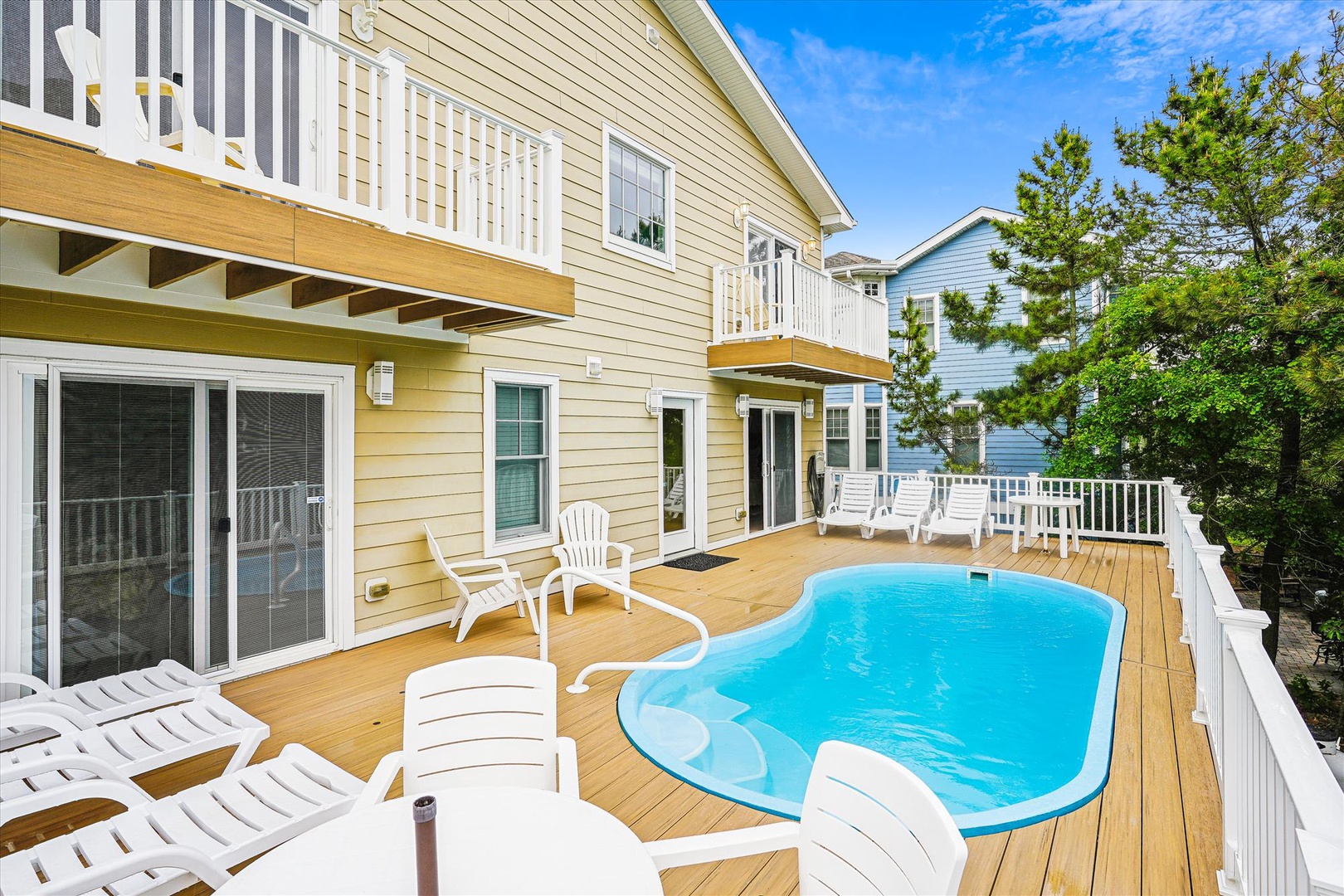 A private, sun-soaked pool deck nestled among coastal greenery, offering relaxing lounging areas and easy access to your comfortable vacation home.