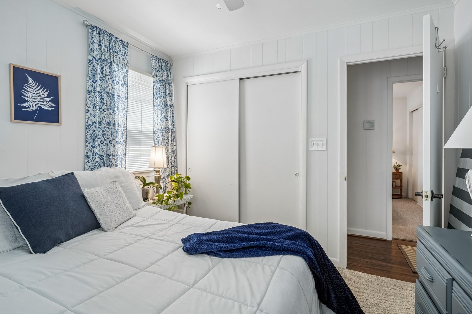 Sink into crisp linens and soft pillows in your serene bedroom retreat, where coastal blues and natural light create a peaceful space for restful sleep.
