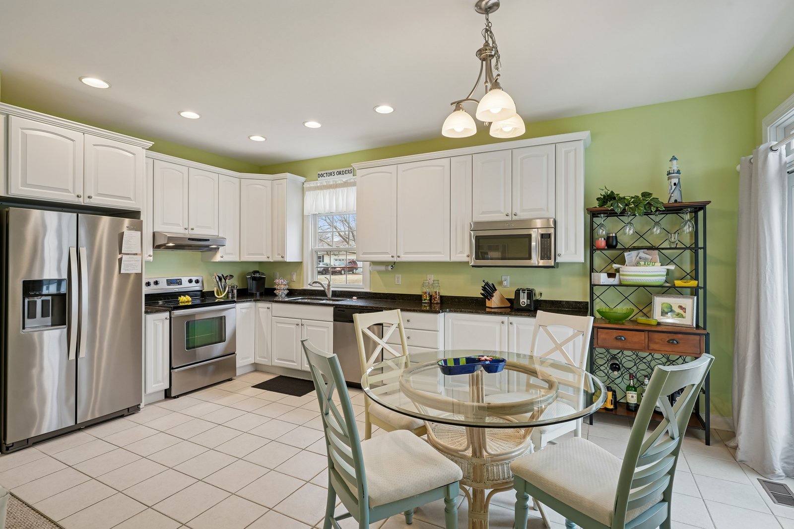 Your spacious kitchen welcomes you with bright green walls, white cabinets, and modern stainless appliances for memorable meal preparation.