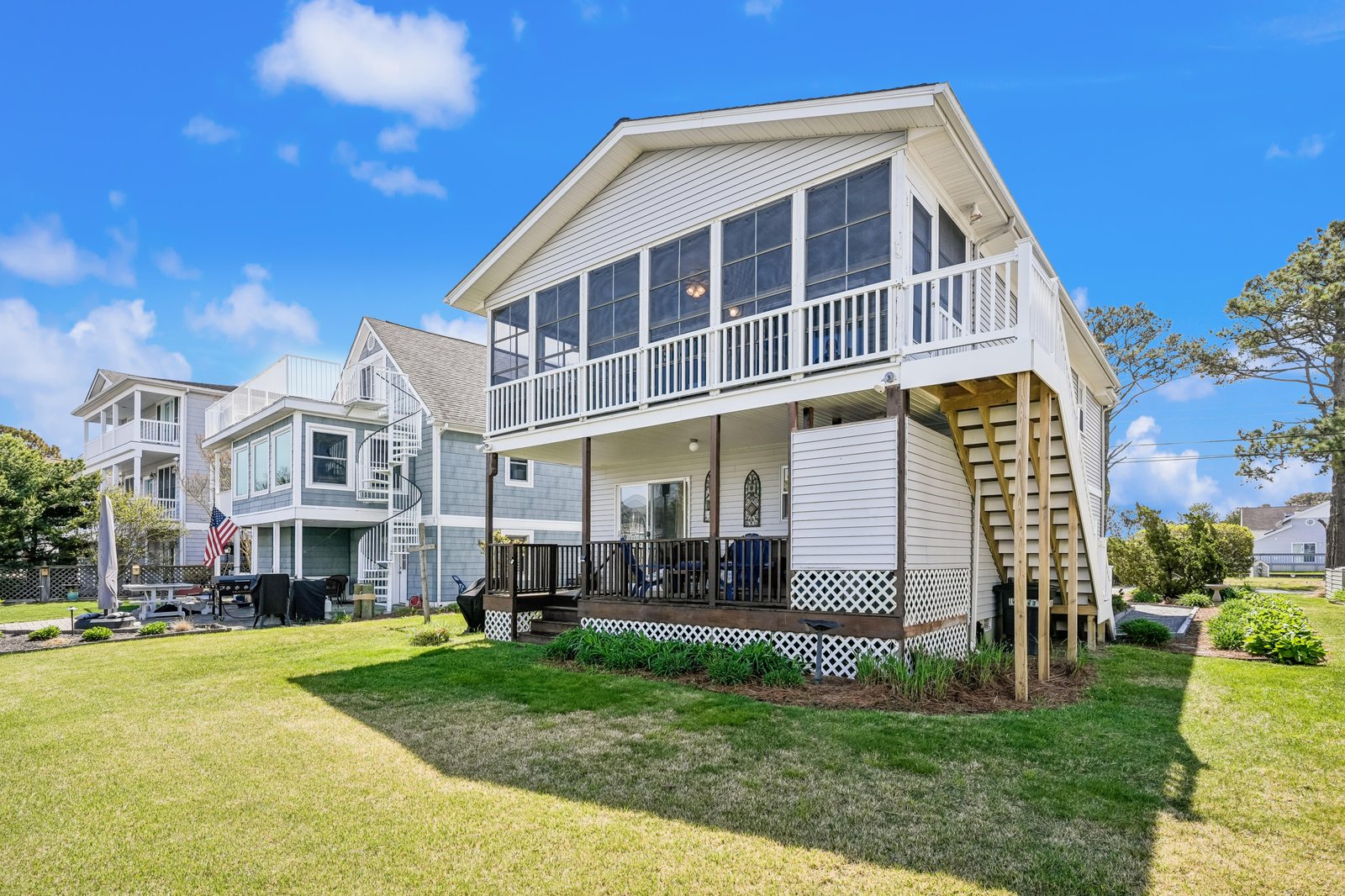 Coastal vacation home with spacious screened porch and landscaped yard, located in a peaceful residential neighborhood near the water.