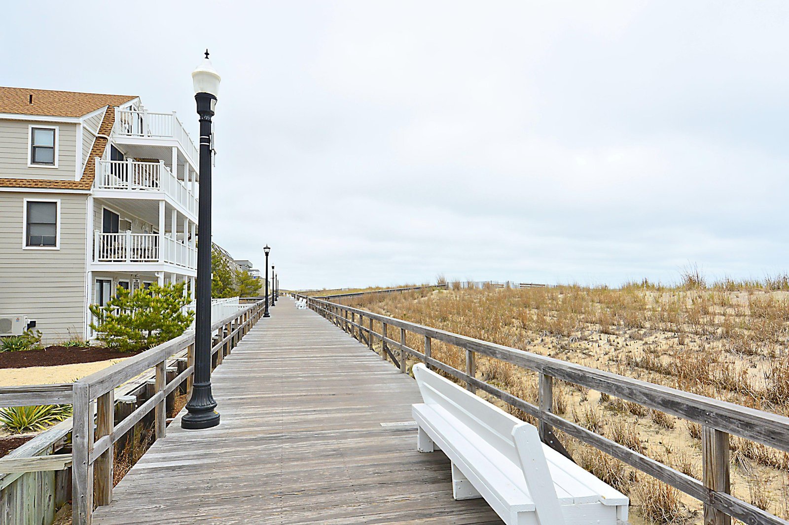 A scenic boardwalk leads from the property toward sandy dunes and beach access, offering a charming stroll through the coastal landscape.