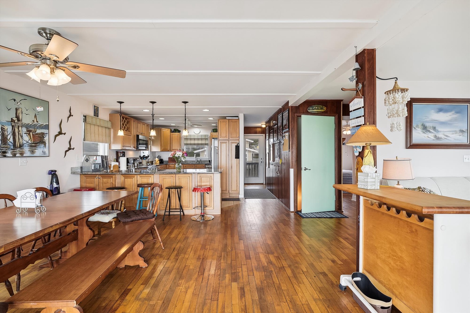 Step into your bright, open-concept vacation home where warm hardwood floors flow from the cozy dining area to a fully-equipped kitchen, all bathed in natural light and nautical charm.