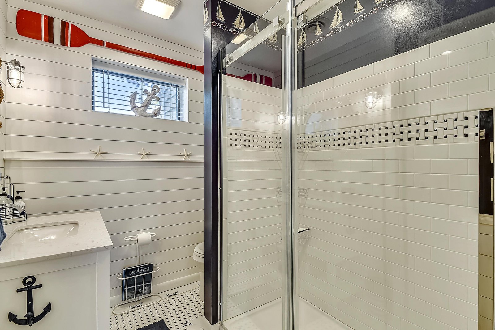 Your private nautical-themed bathroom features crisp white tile, a spacious walk-in shower, and charming maritime accents throughout.