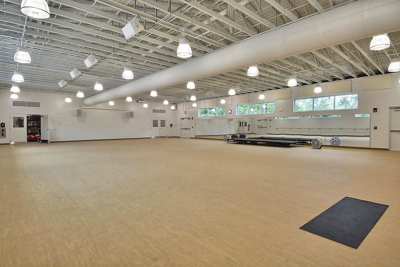 A spacious multipurpose indoor area with natural light streaming through high windows, offering plenty of room for gatherings, events, or activities during your stay.