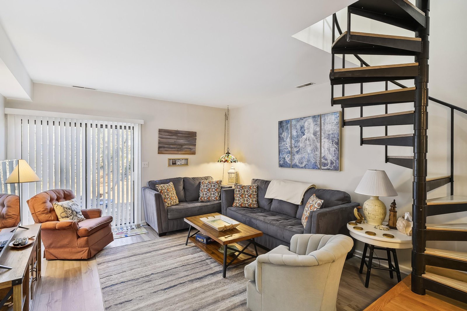 Settle into your welcoming living room, where plush seating and natural light create the perfect retreat. The striking spiral staircase adds character as you unwind.