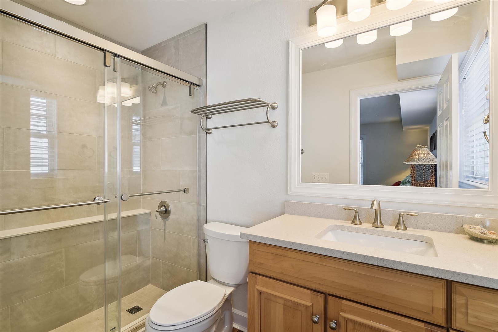 Refresh in your private bathroom featuring a sleek glass shower, modern vanity, and warm lighting for your daily routine.
