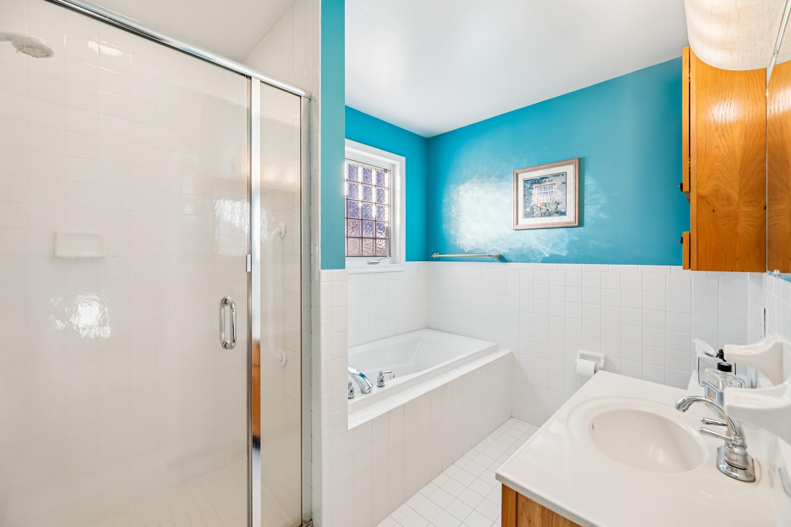 Relax in your spacious private bathroom with a soaking tub and separate glass-enclosed shower. The cheerful turquoise walls and white tile create a fresh, coastal feel, perfect for unwinding after exploring nearby beaches.