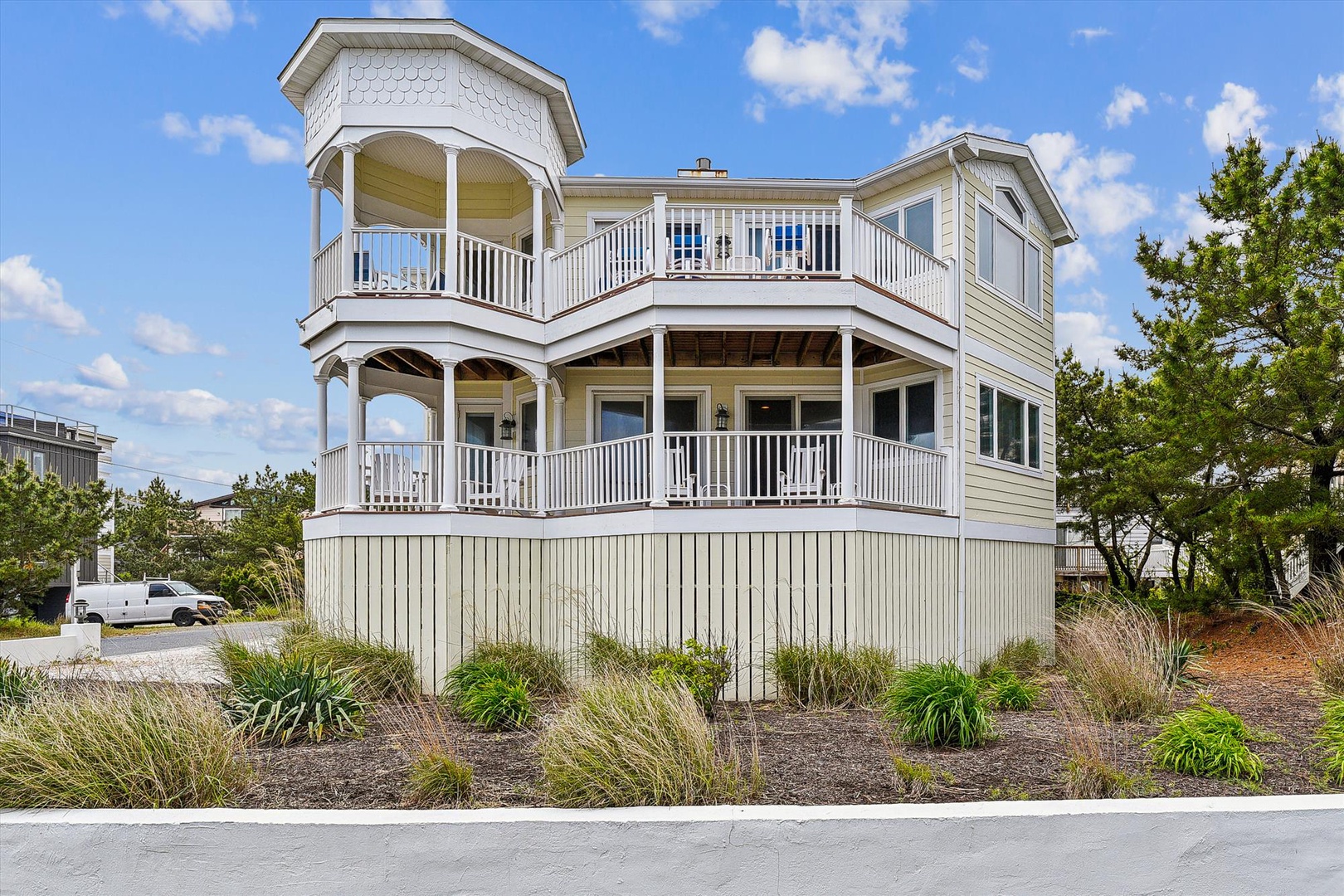 A distinctive two-story beachside property featuring wraparound balconies and coastal landscaping, located in a quiet neighborhood with convenient parking access.