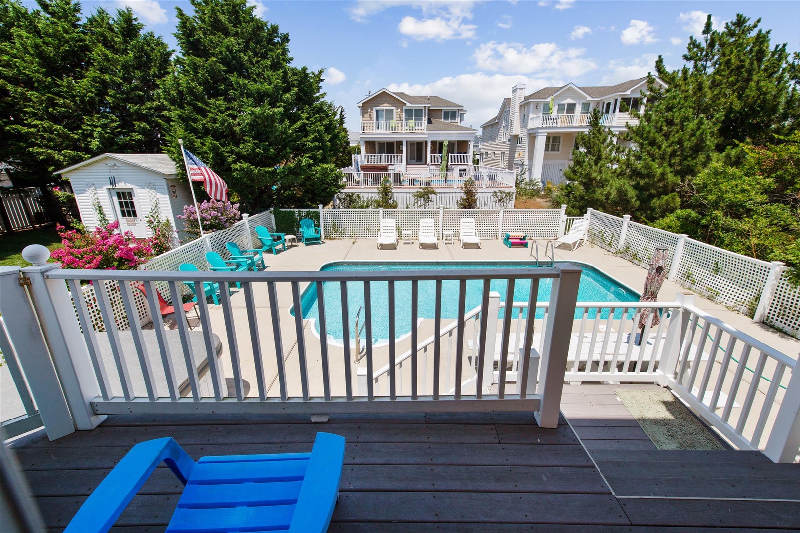 Your private deck overlooks a sparkling pool surrounded by turquoise loungers, lush trees, and coastal charm—perfect for soaking up sunny afternoons and poolside relaxation.